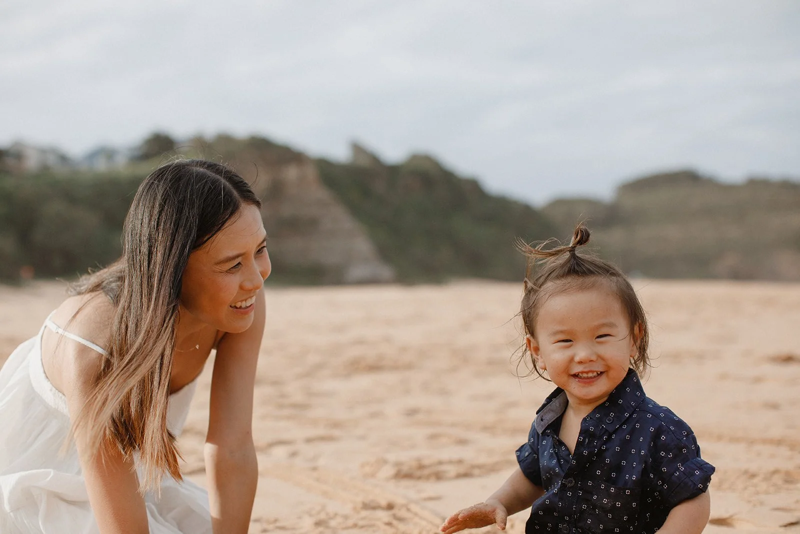 Woman with long brown hair on beach with toddler