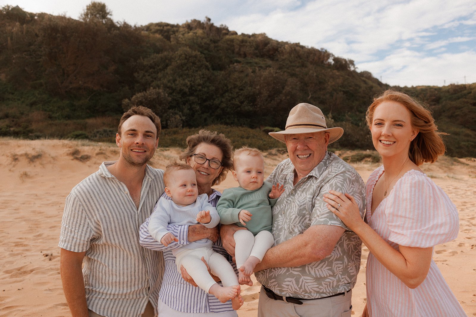 Parents and grandparents with twin baby boys on the beach