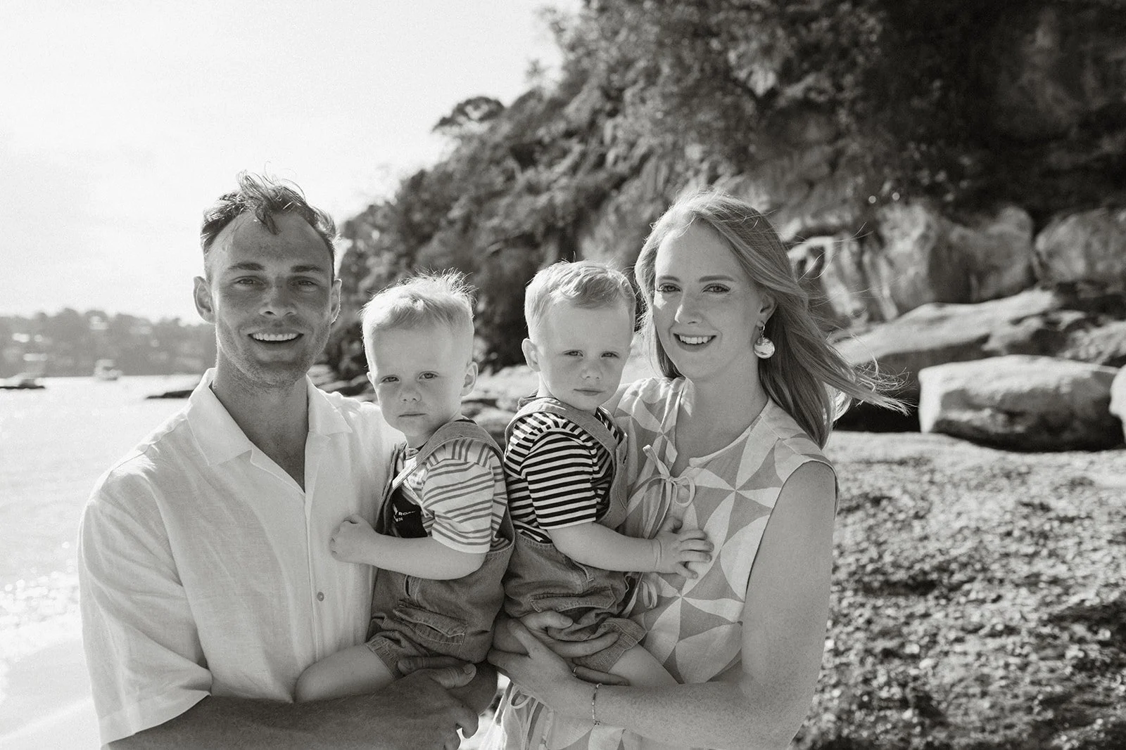 Parents holding toddler boys on beach