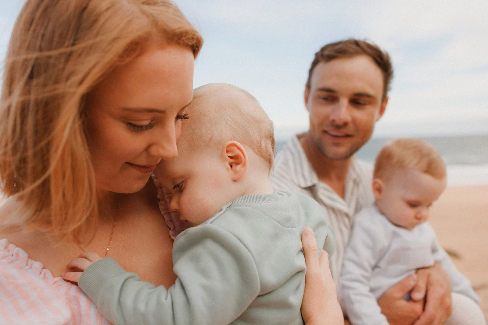 Parents holding  baby boys on the beach