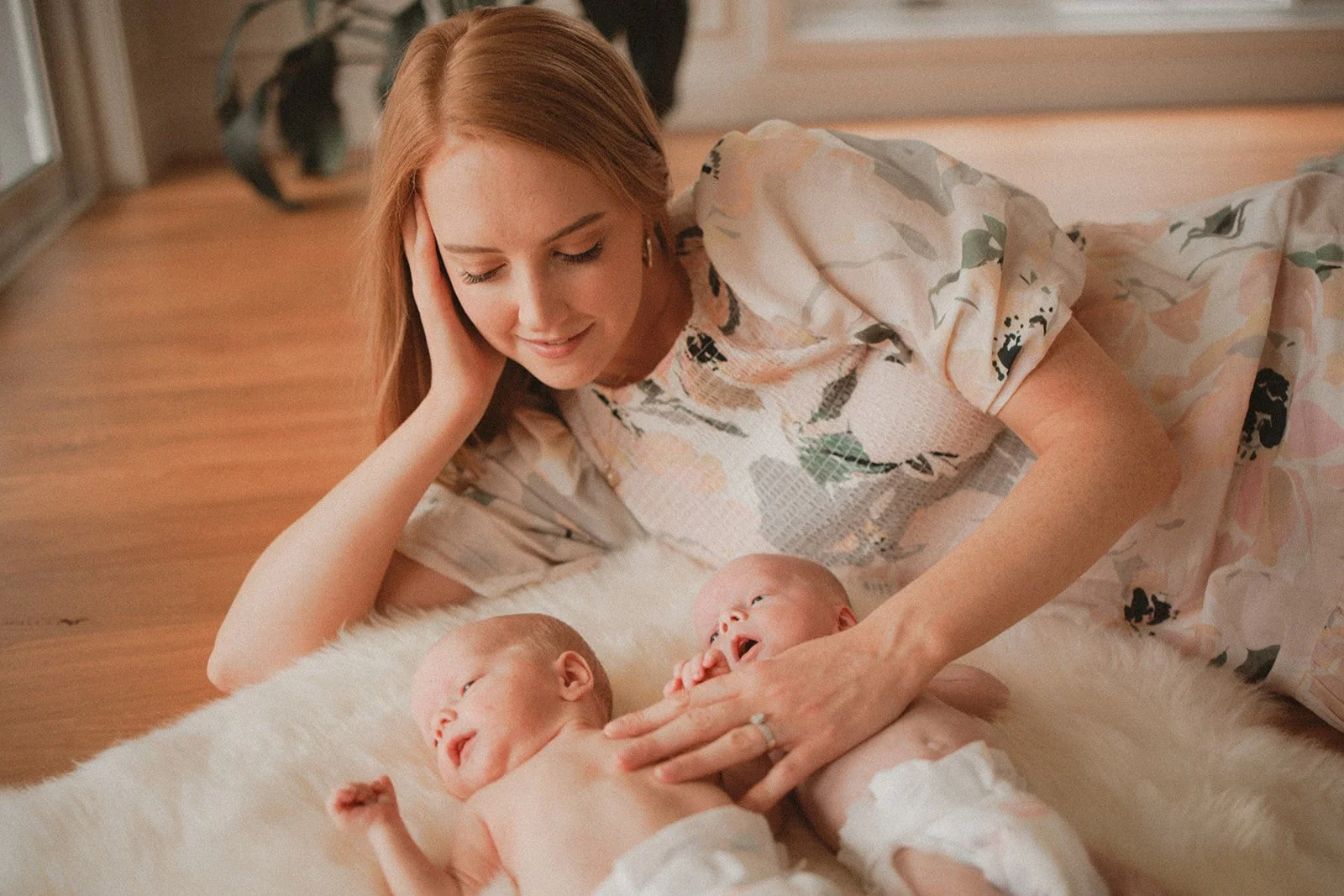 New mum lying on floor with newborn twin babies