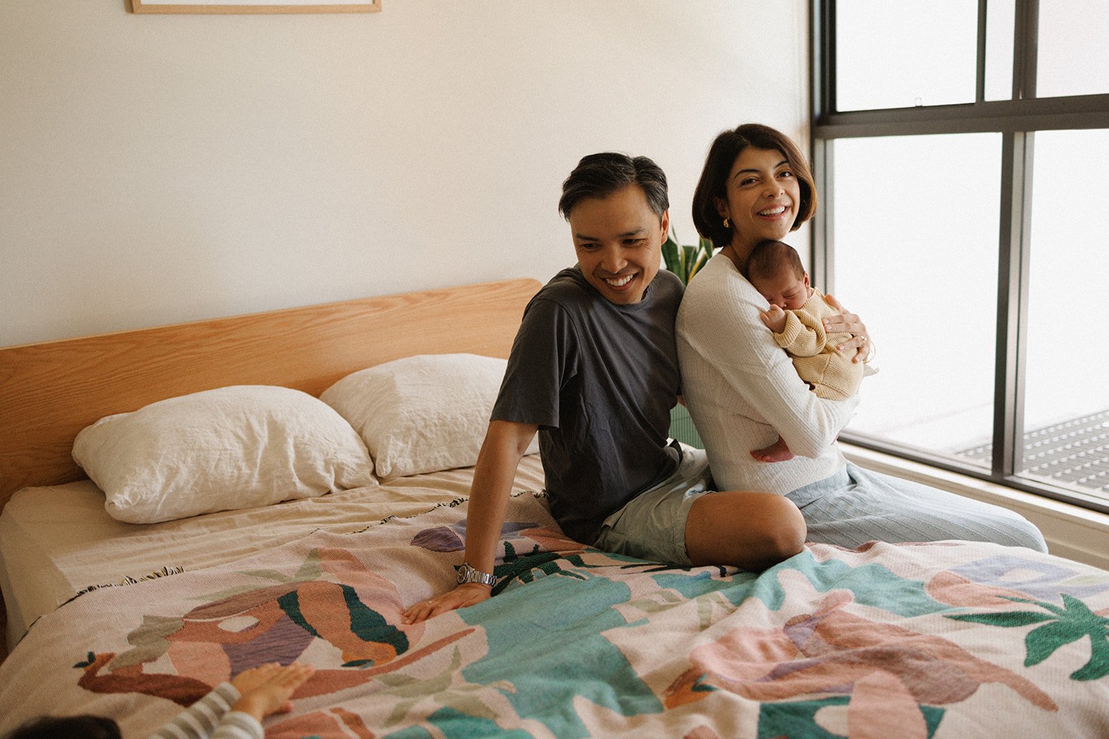 Couple sitting on bed with newborn baby