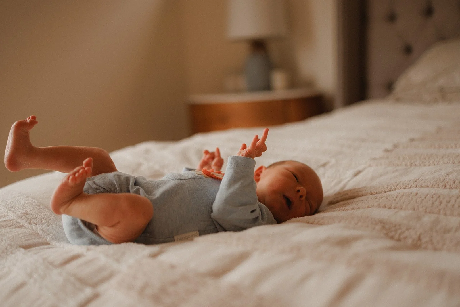 Newborn baby in blue outfit lying on bed