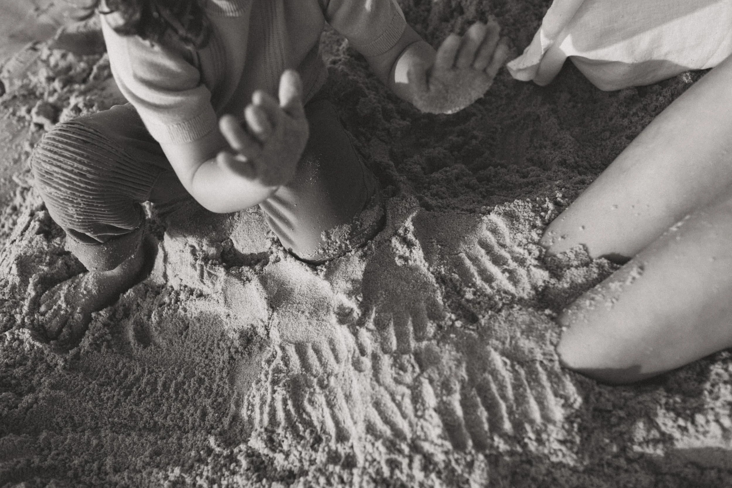 Toddler playing in the sand with mum
