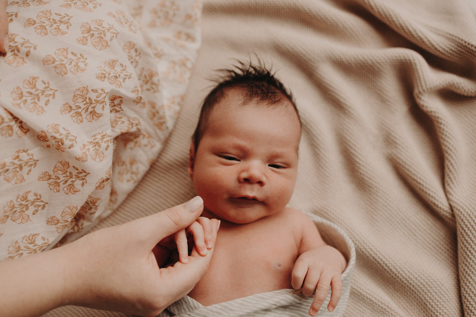 Newborn baby holding mother's hand