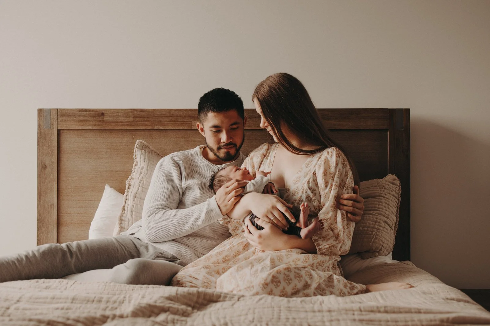 Newborn baby with parents on bed
