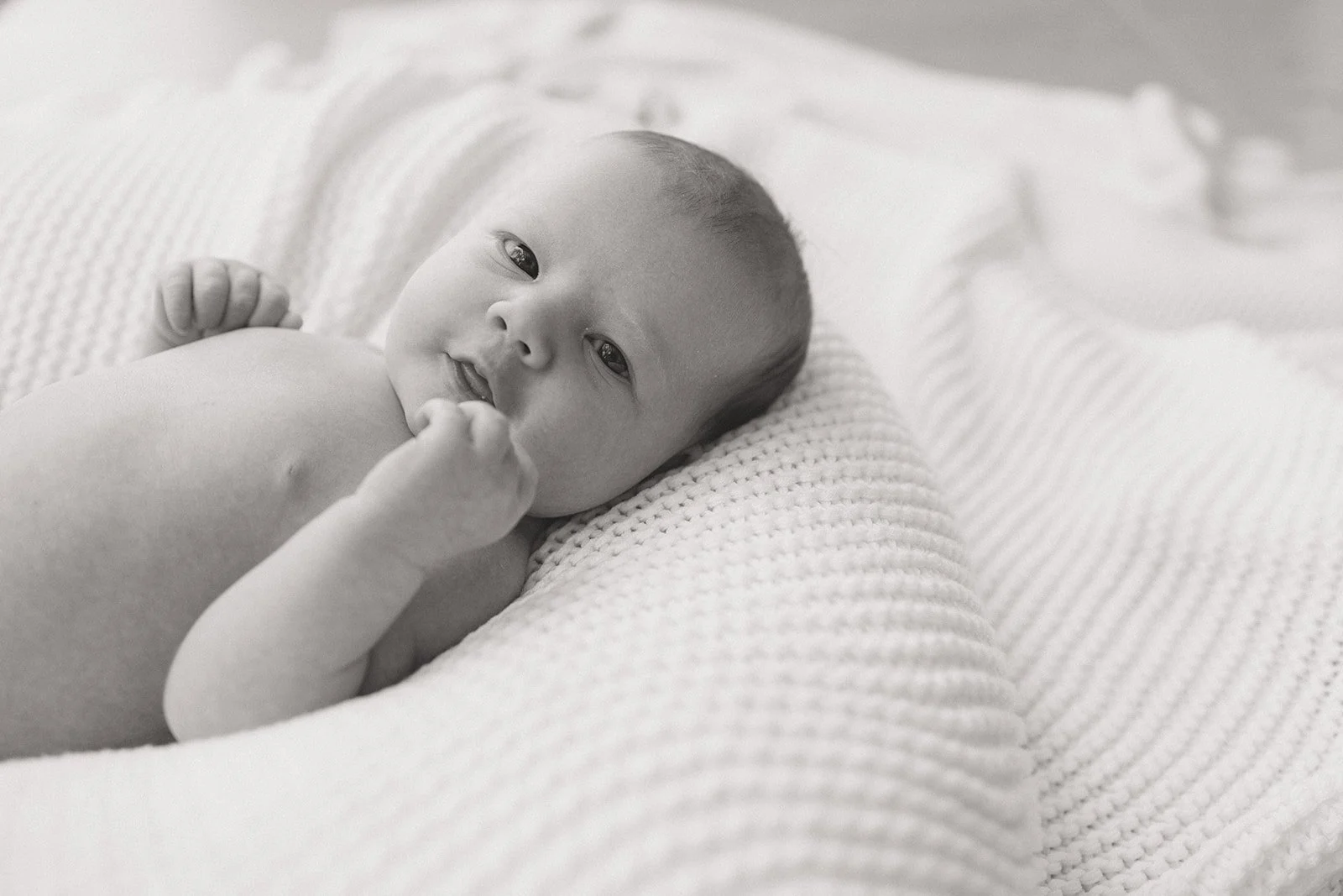 Newborn baby lying on knitted blanket