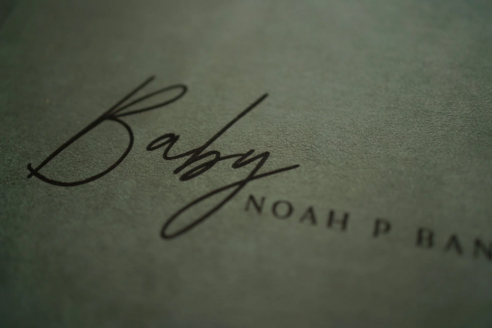 Close-up of a textured surface with handwritten text that reads 'Baby Noah P.' in black ink.