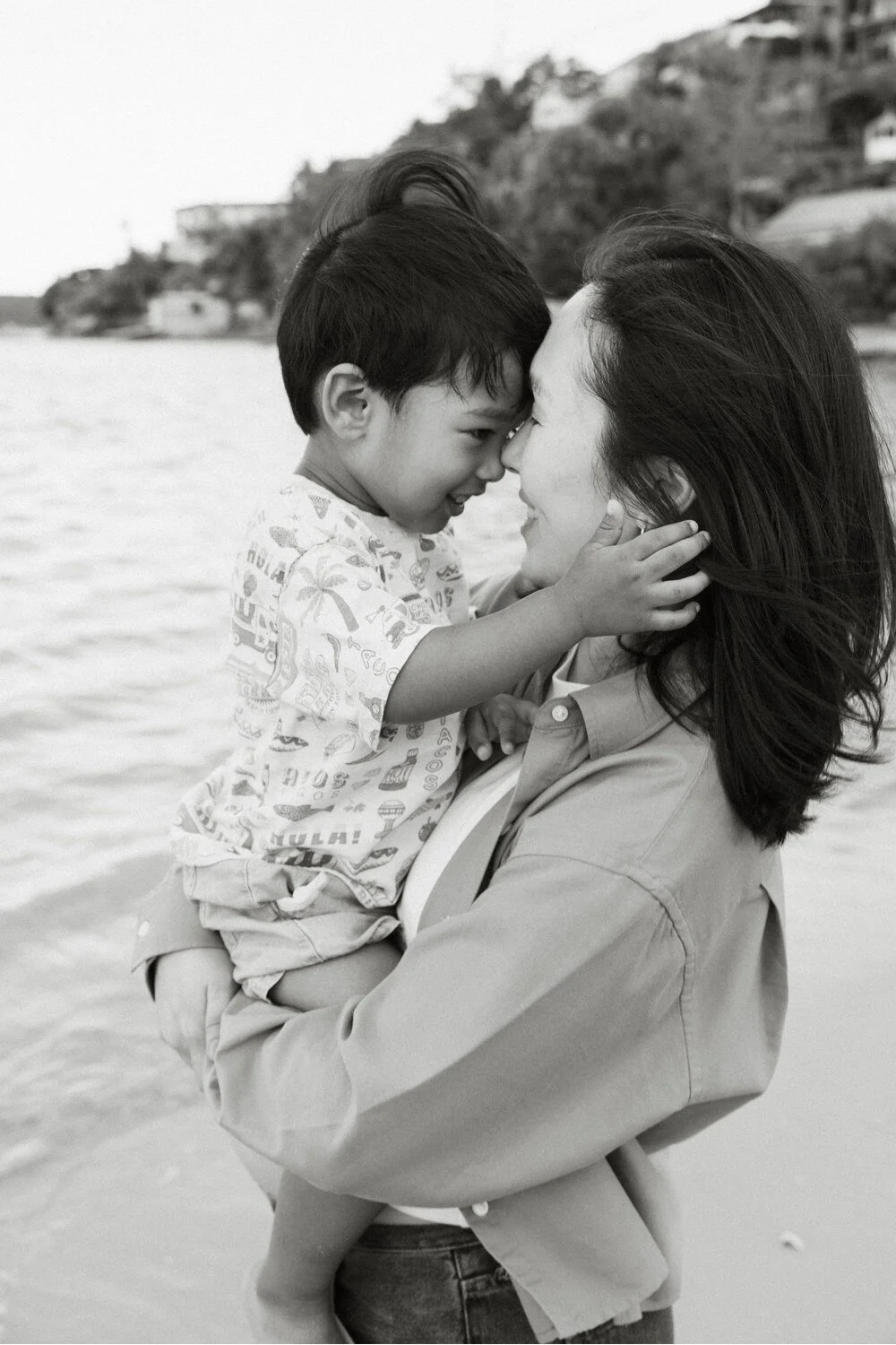 Close-up connection: Black and white portrait of a mother and toddler touching foreheads.