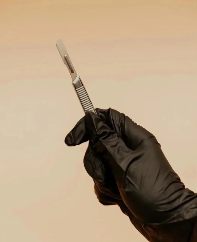 A person wearing black gloves holds a small knife, demonstrating careful handling of the tool.