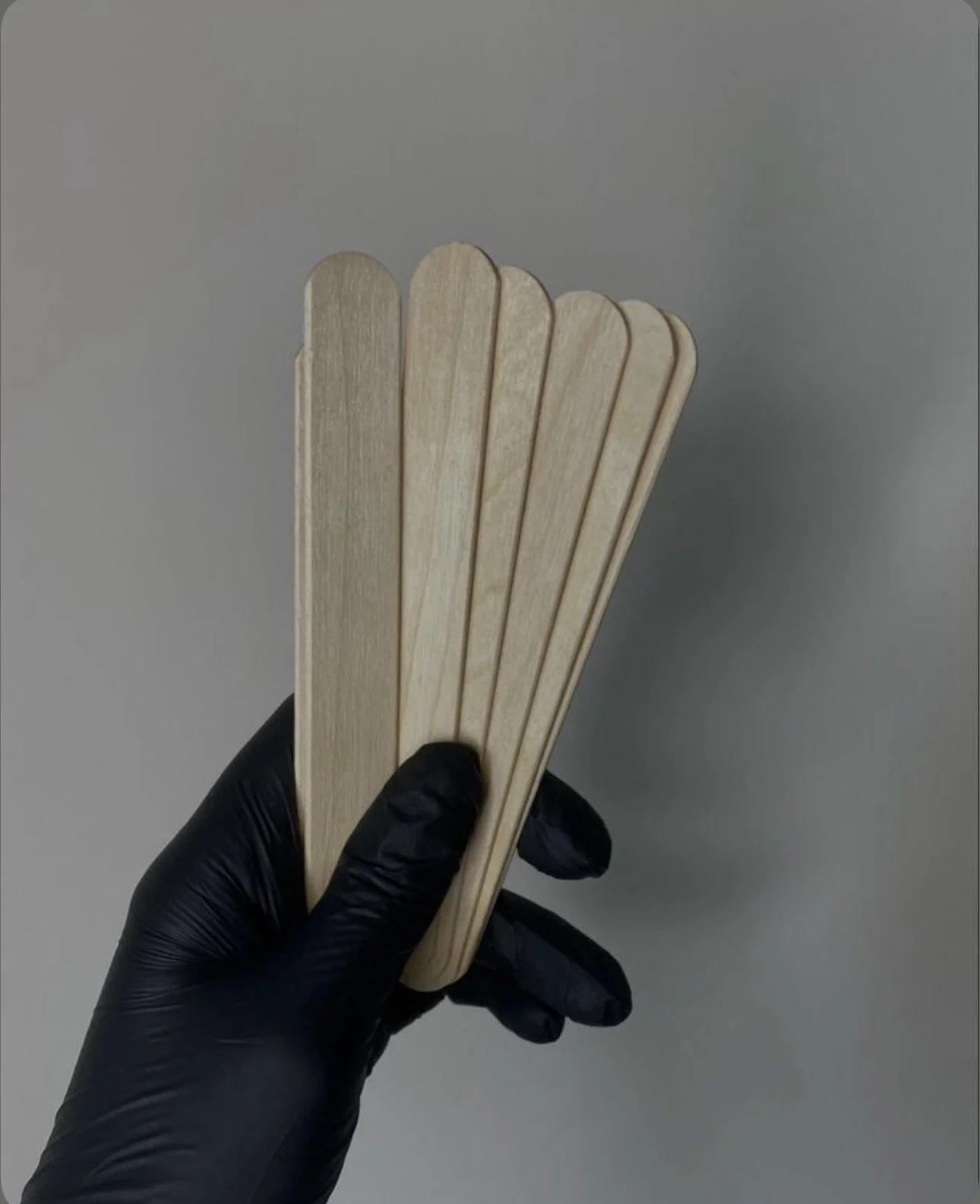 A person holding four wooden sticks in their hand, showcasing a variety of lengths and textures.