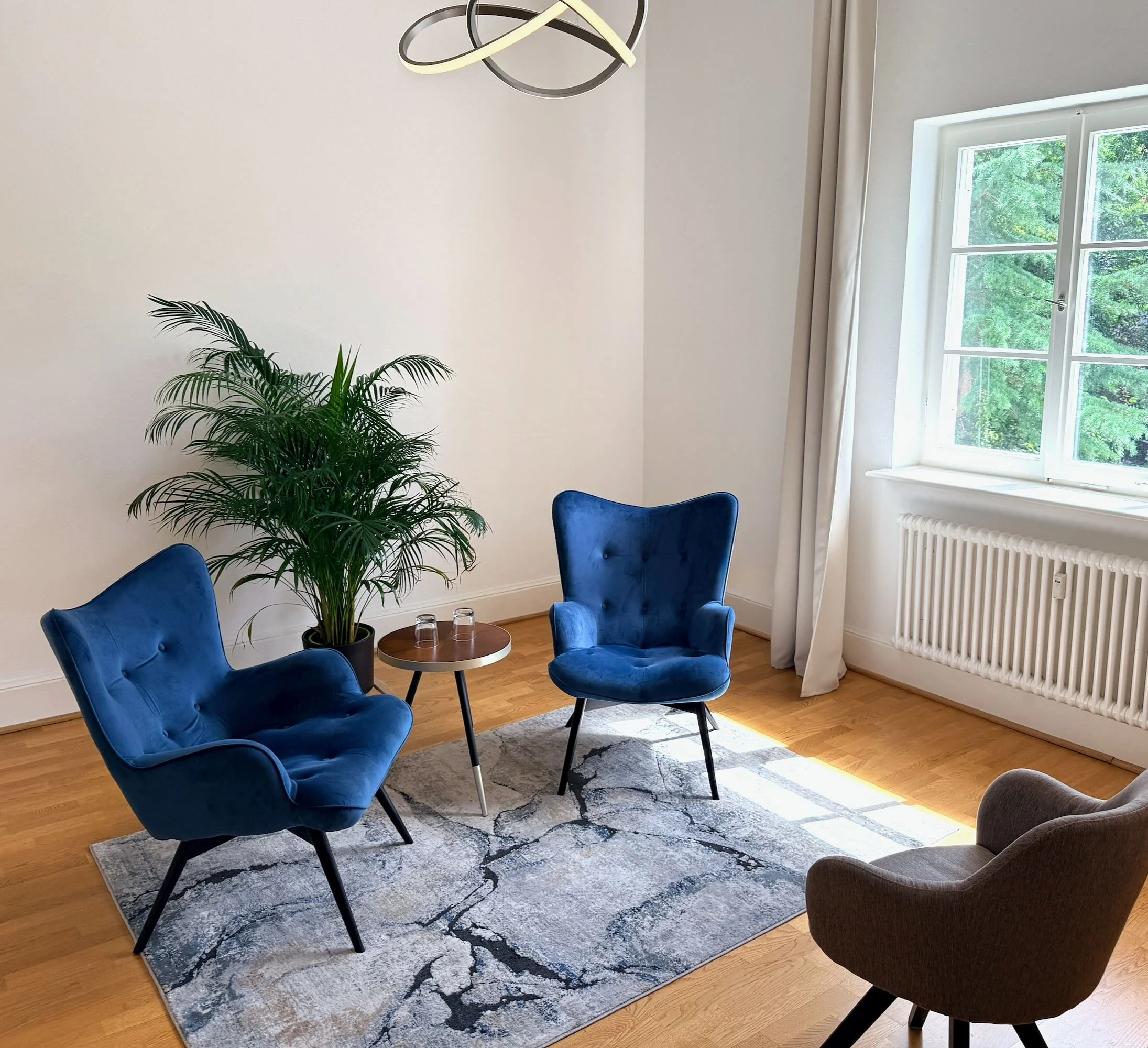 Gemütlicher sonniger Therapieraum mit zwei bequemen blauen Stühlen