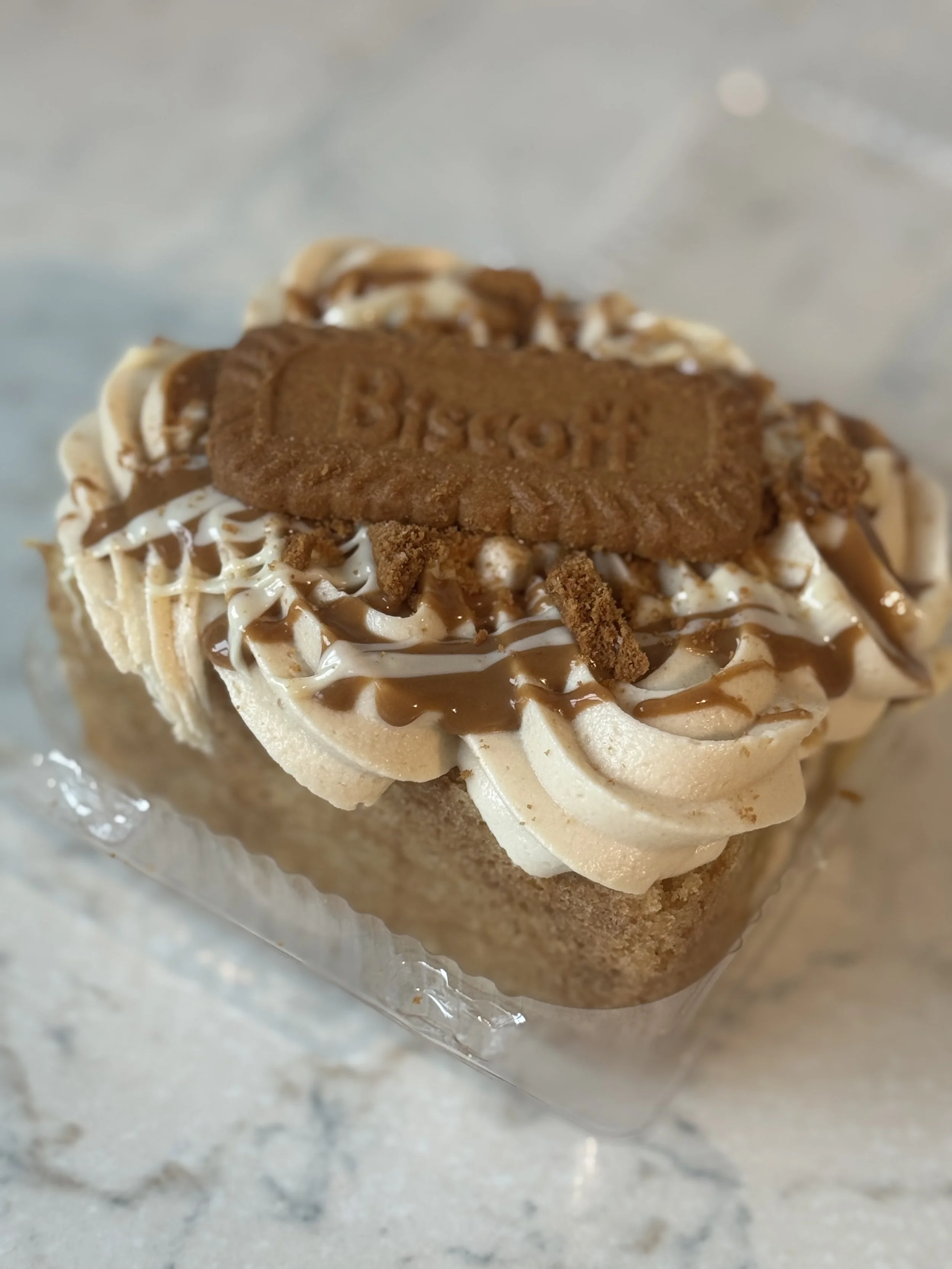 biscoff loaded cake slice. biscoff buttercream topped with biscoff and white chocolate drizzle.