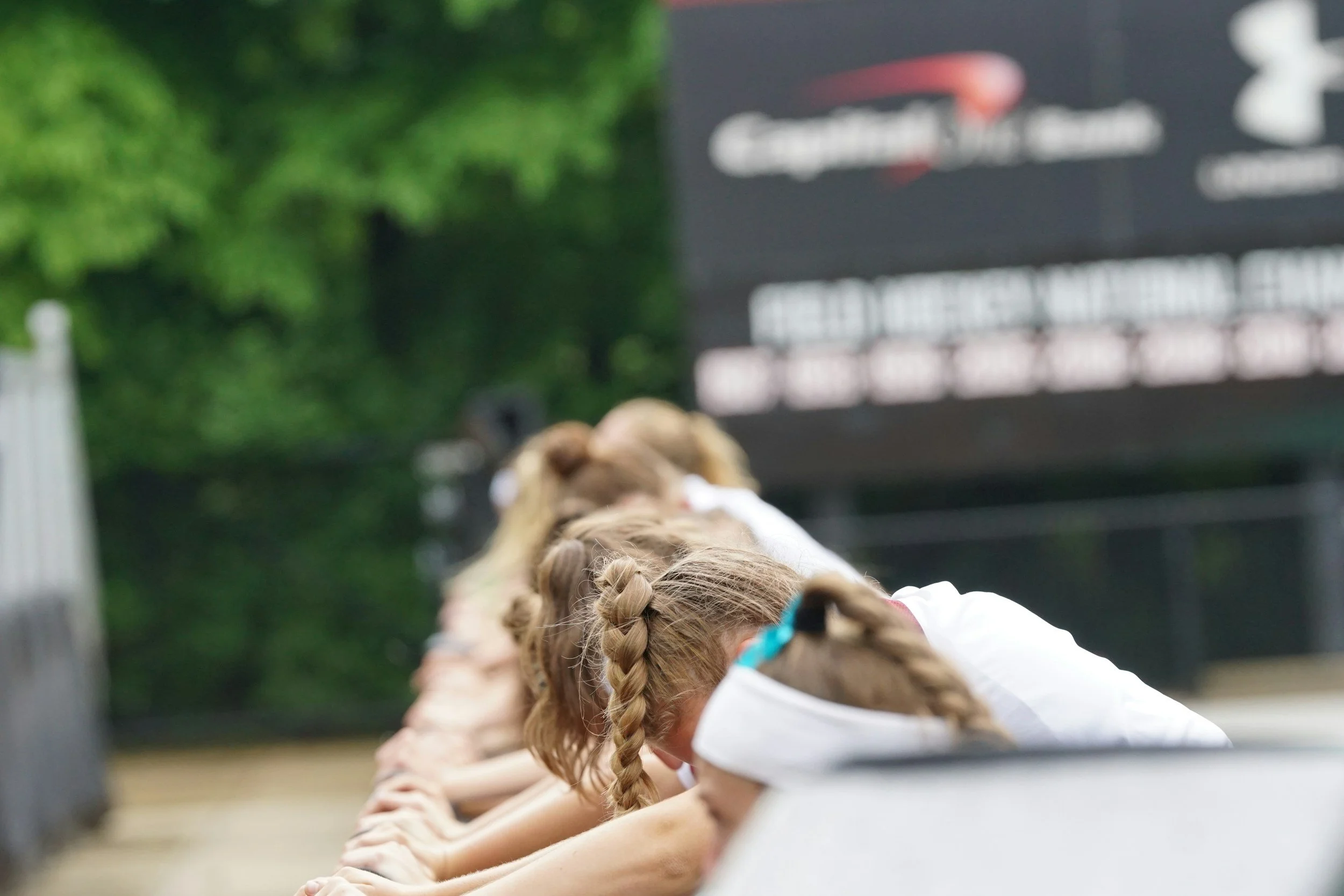Children with braided hair doing a plank exercise on the floor outdoors during daytime.