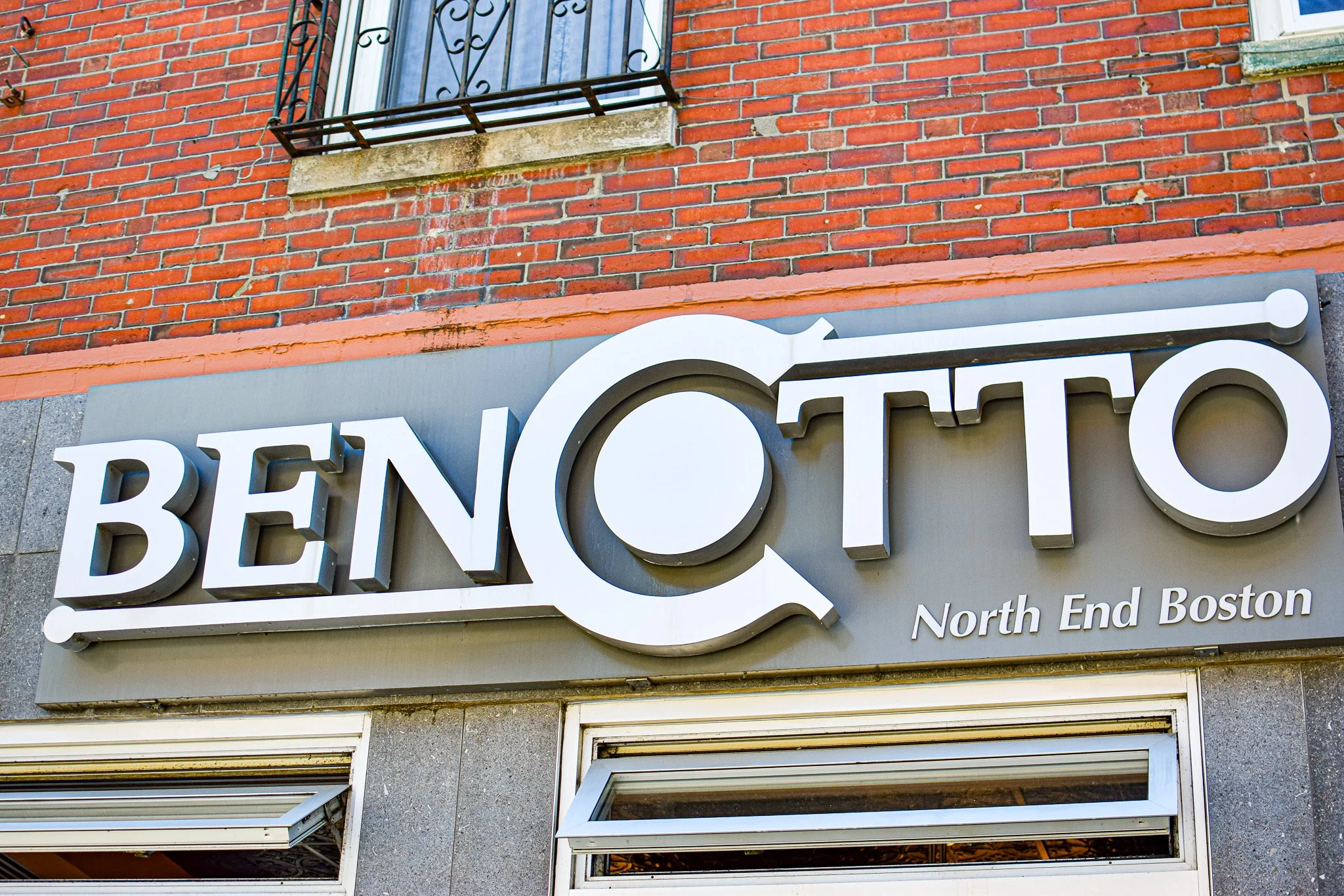 Close-up of a building's exterior with a partial view of a sign saying "BENCOTTO".