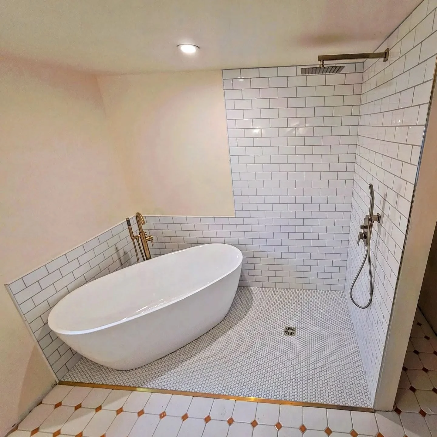 Bathroom with a white freestanding tub, brass fixtures, and a walk-in shower with white subway tile walls and a rainfall showerhead.