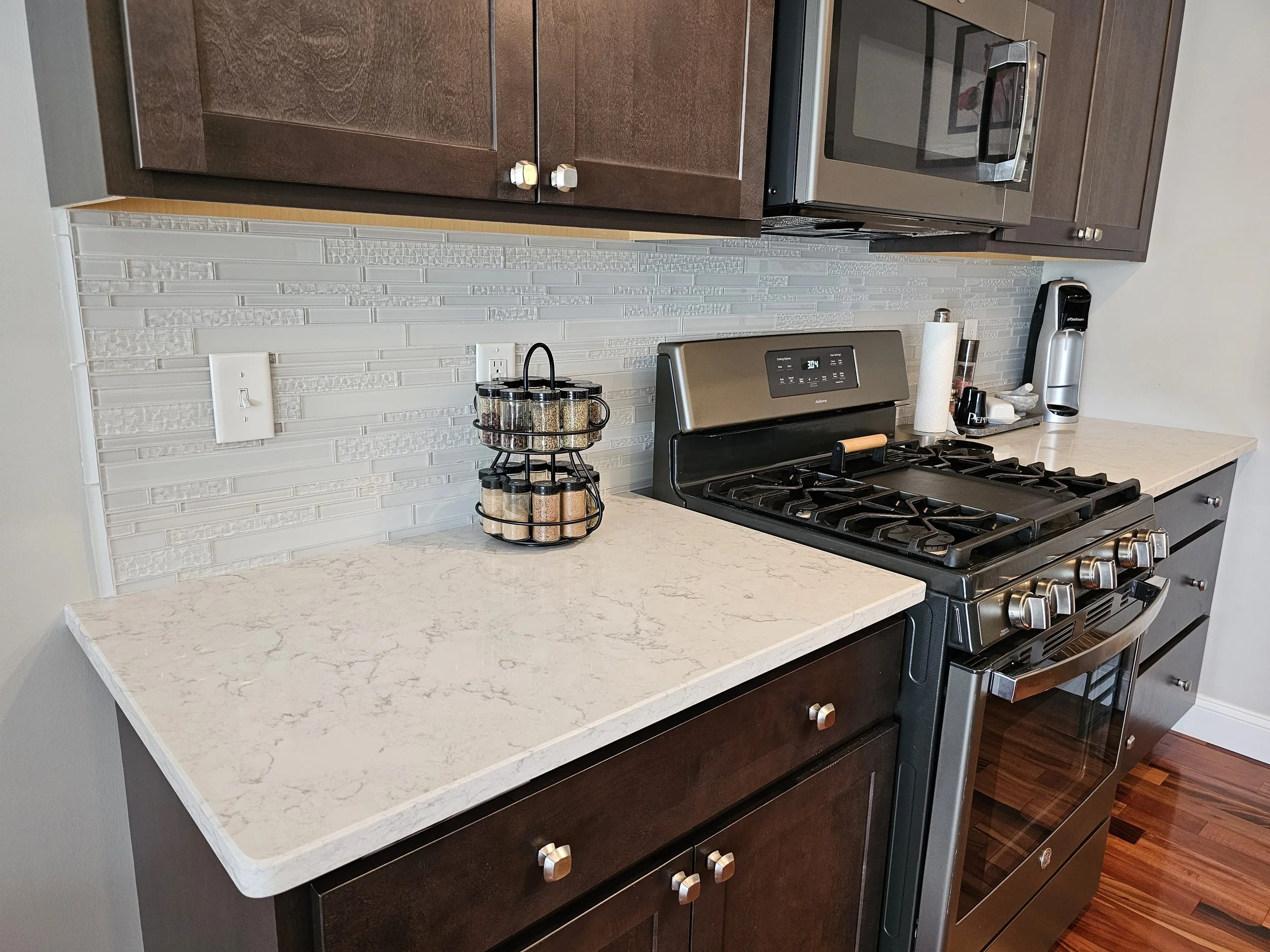 Kitchen countertop with spice jars, paper towel, and appliances including a stove, microwave, and a coffee maker.