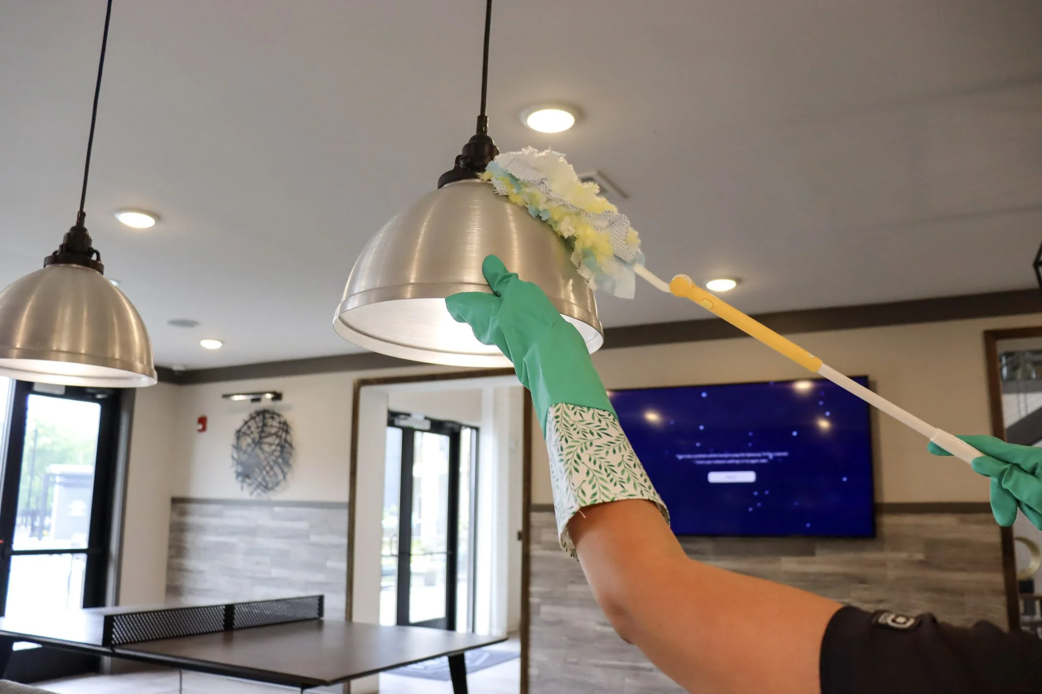 Dusting a ceiling light fixture during routine home cleaning