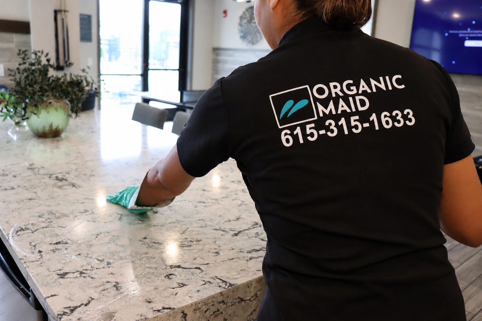 Professional house cleaner disinfecting a marble countertop with eco-friendly cleaning products