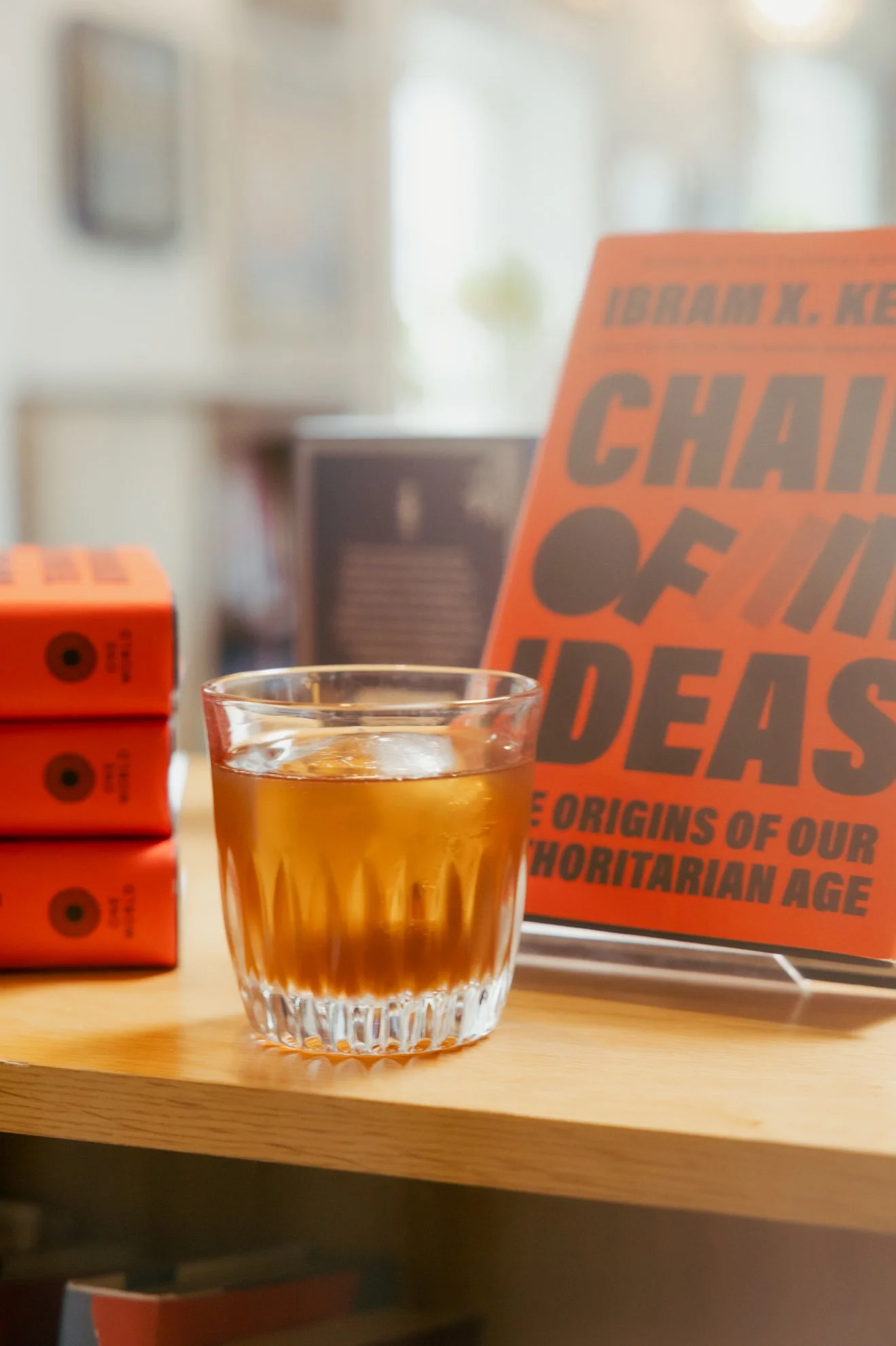 A glass of iced tea on a wooden table with a magazine about Barack K. Obama in the background.