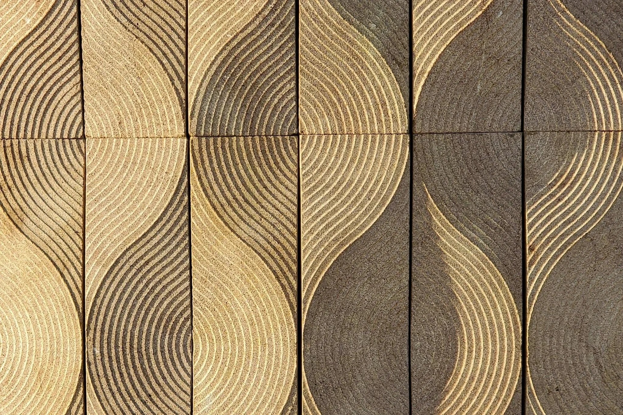 Close-up of several wooden planks showing growth rings and textures, arranged vertically.