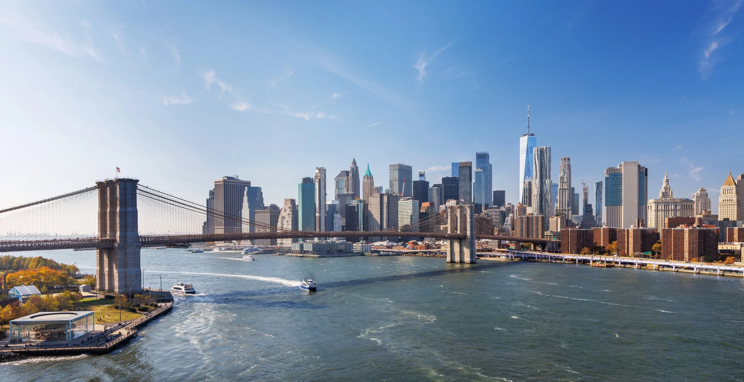 View of New York City skyline with the Brooklyn Bridge over the East River on a clear day.