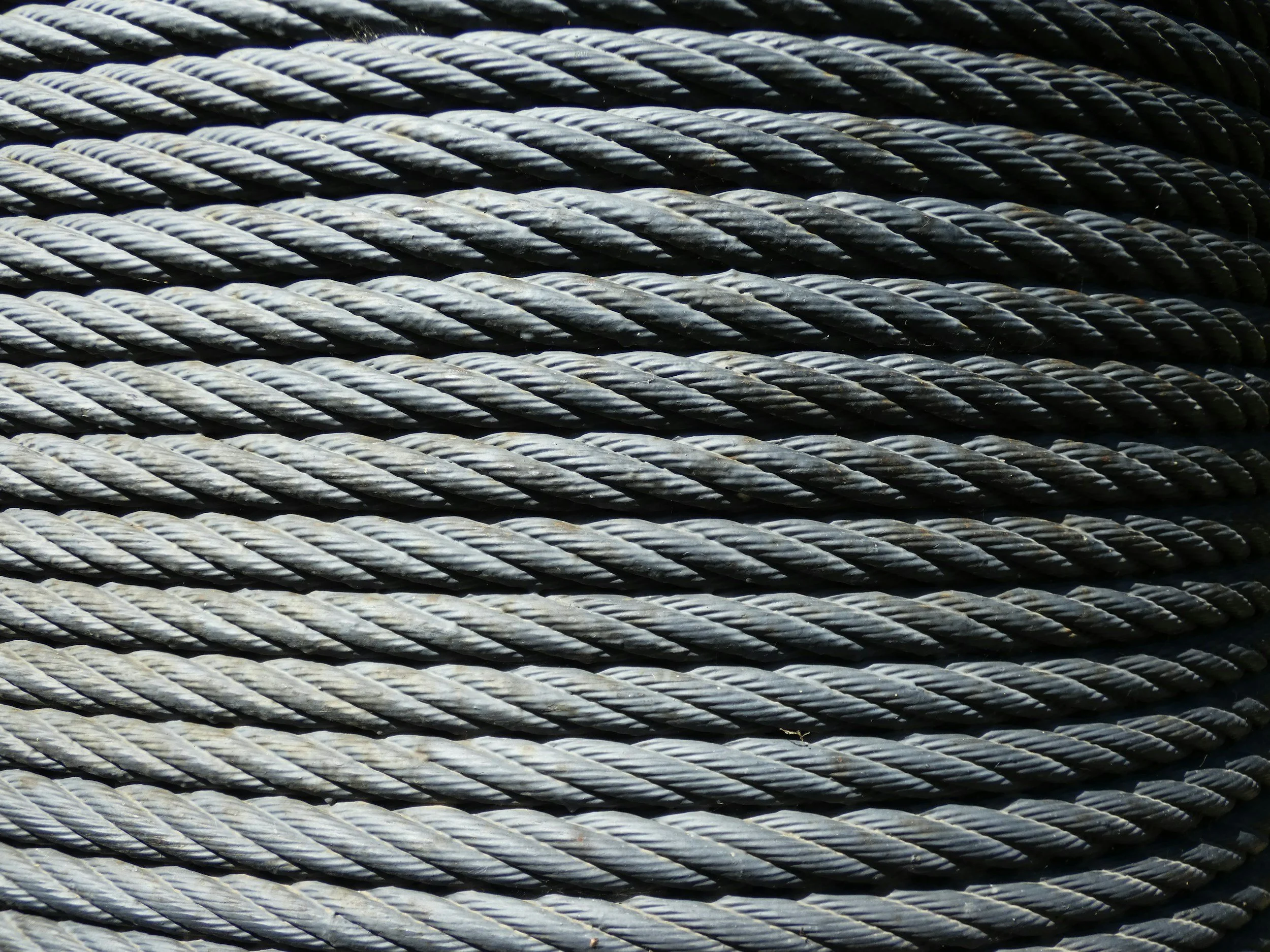 Close-up of multiple thick, gray steel cables stacked horizontally.