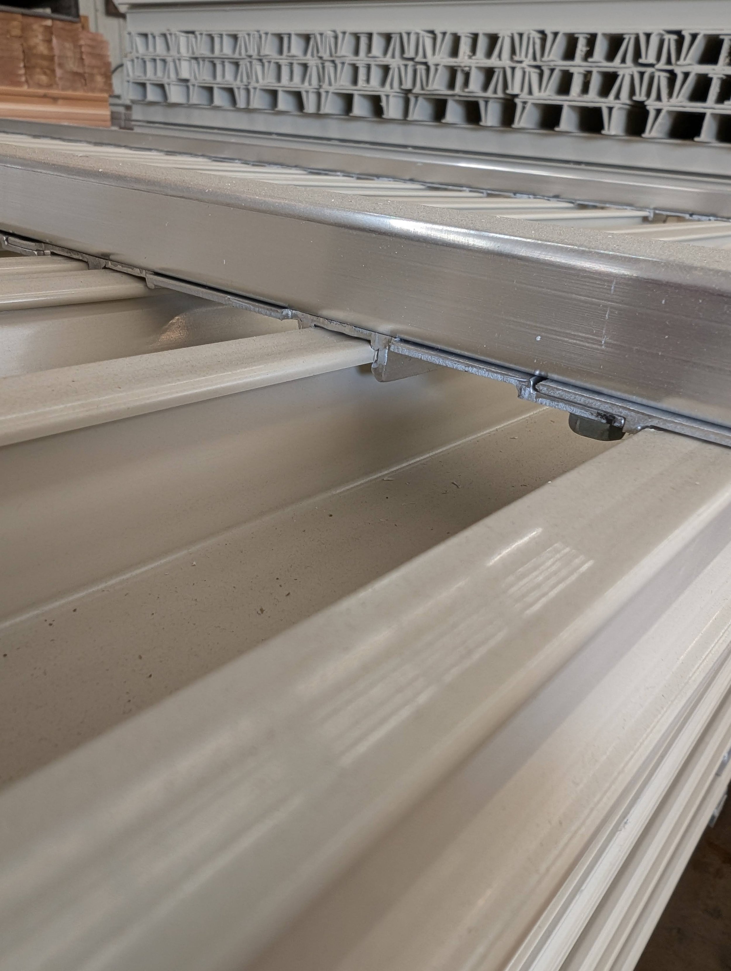 Metal shelving unit with empty beige plastic bins and some wooden cabinetry in the background.