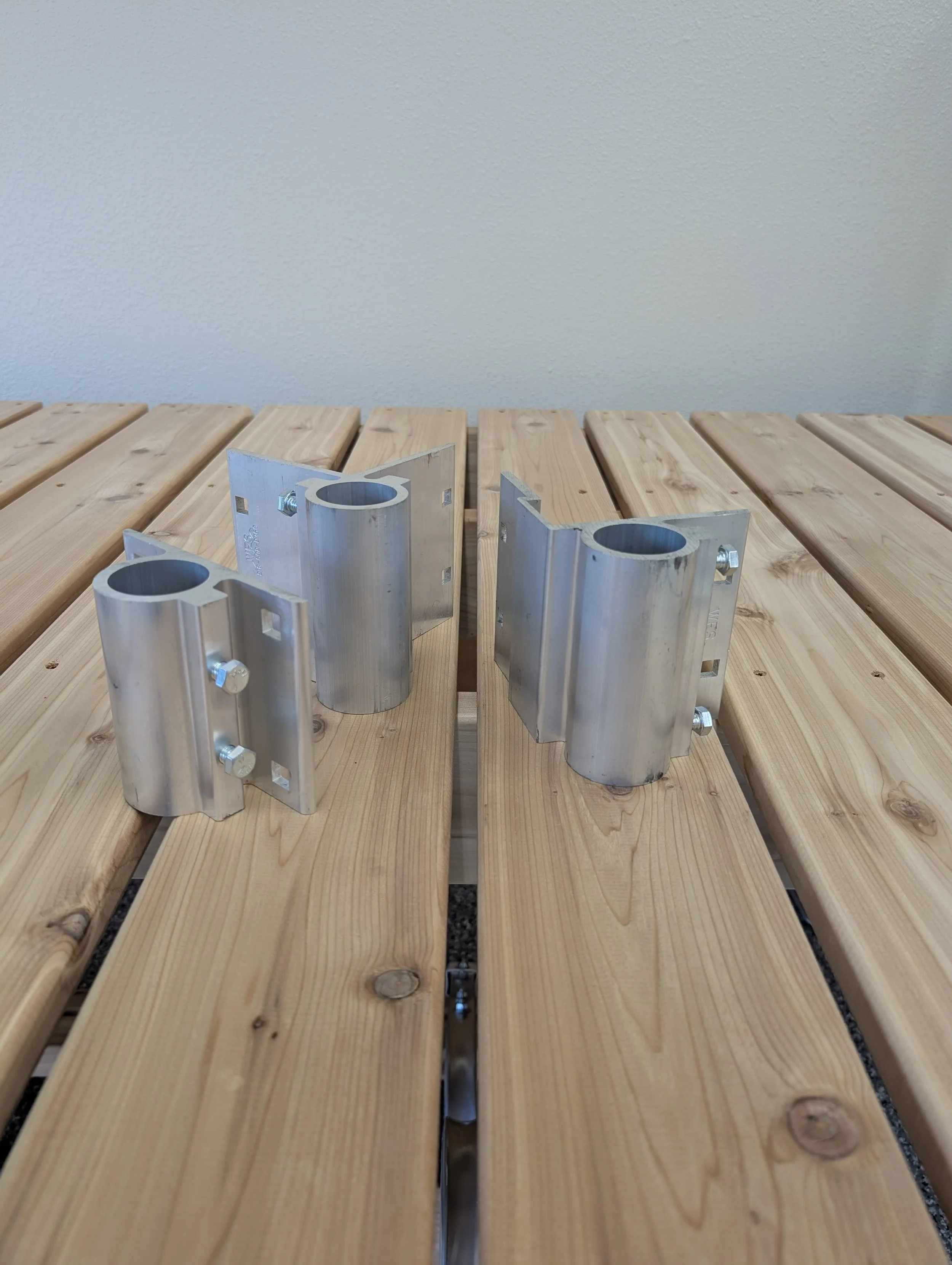 Close-up of metal brackets and wood planks on a wooden surface, with a plain wall in the background.