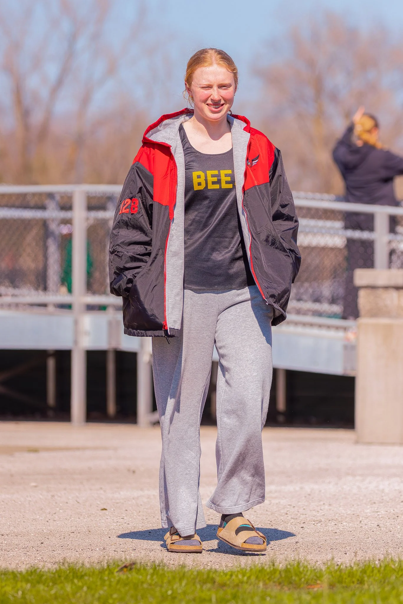A young female fielder smiles at the camera as she walks.