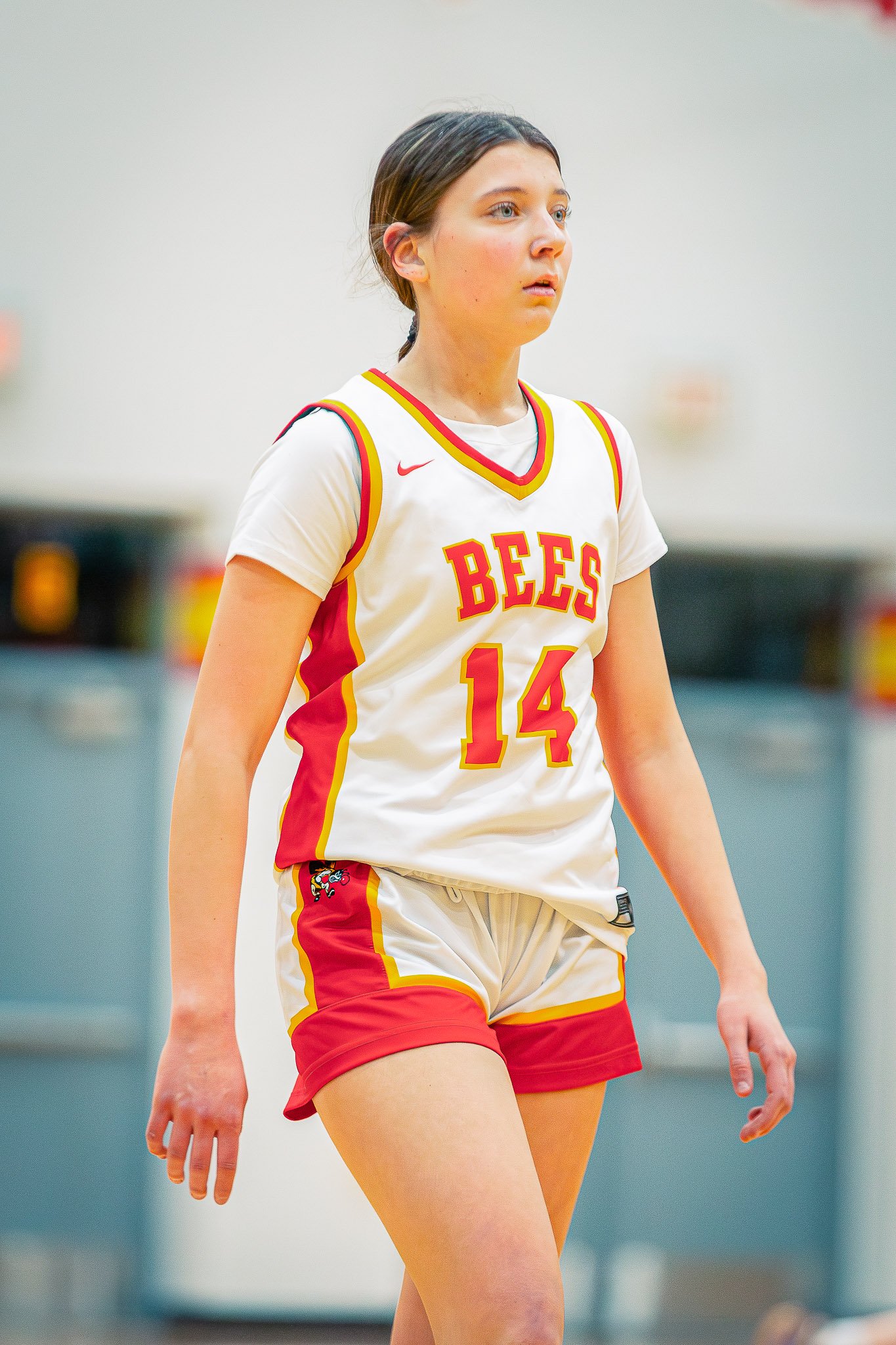 A female basketball player wearing a white and red jersey with the number 14 on it, standing on a basketball court.