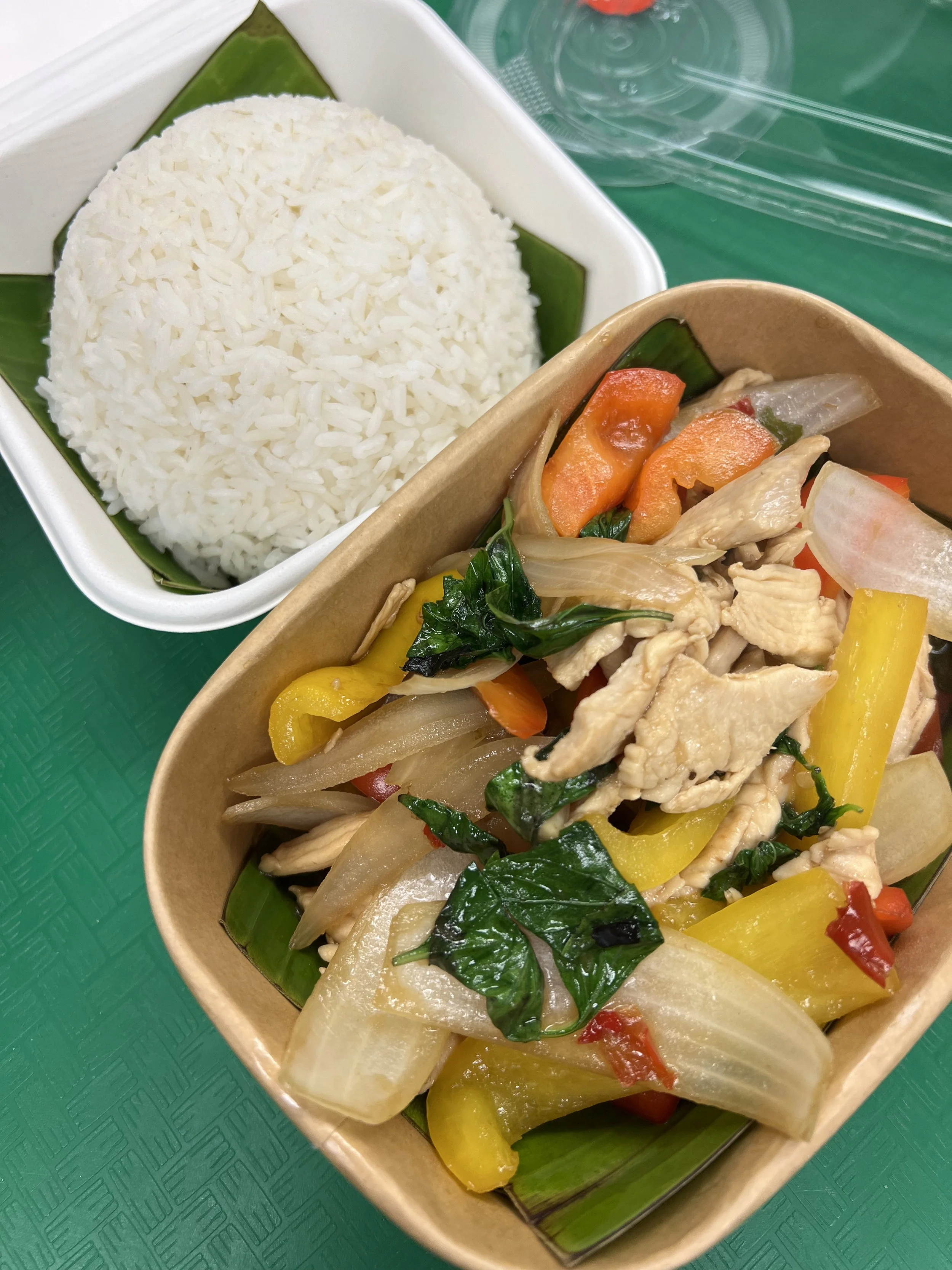 White rice served with a side of stir-fried vegetables and chicken in a cardboard container.