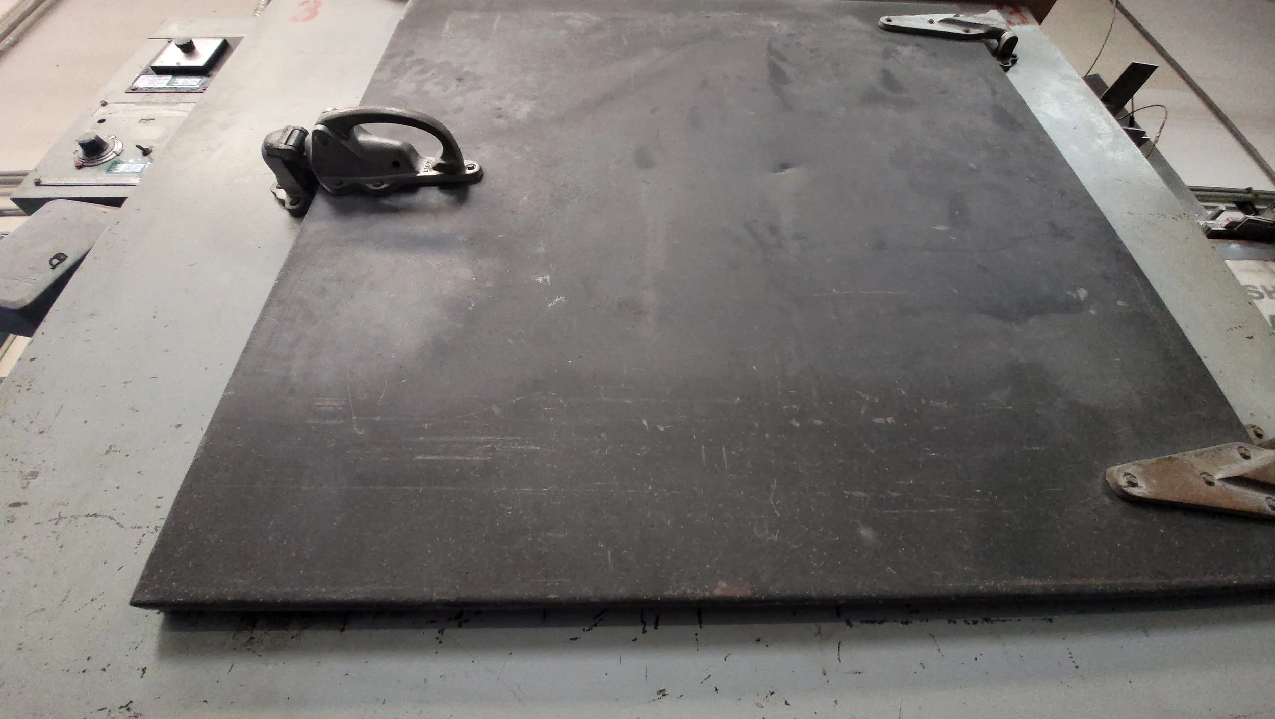 A large metal worktable in a workshop with various tools and equipment around it.