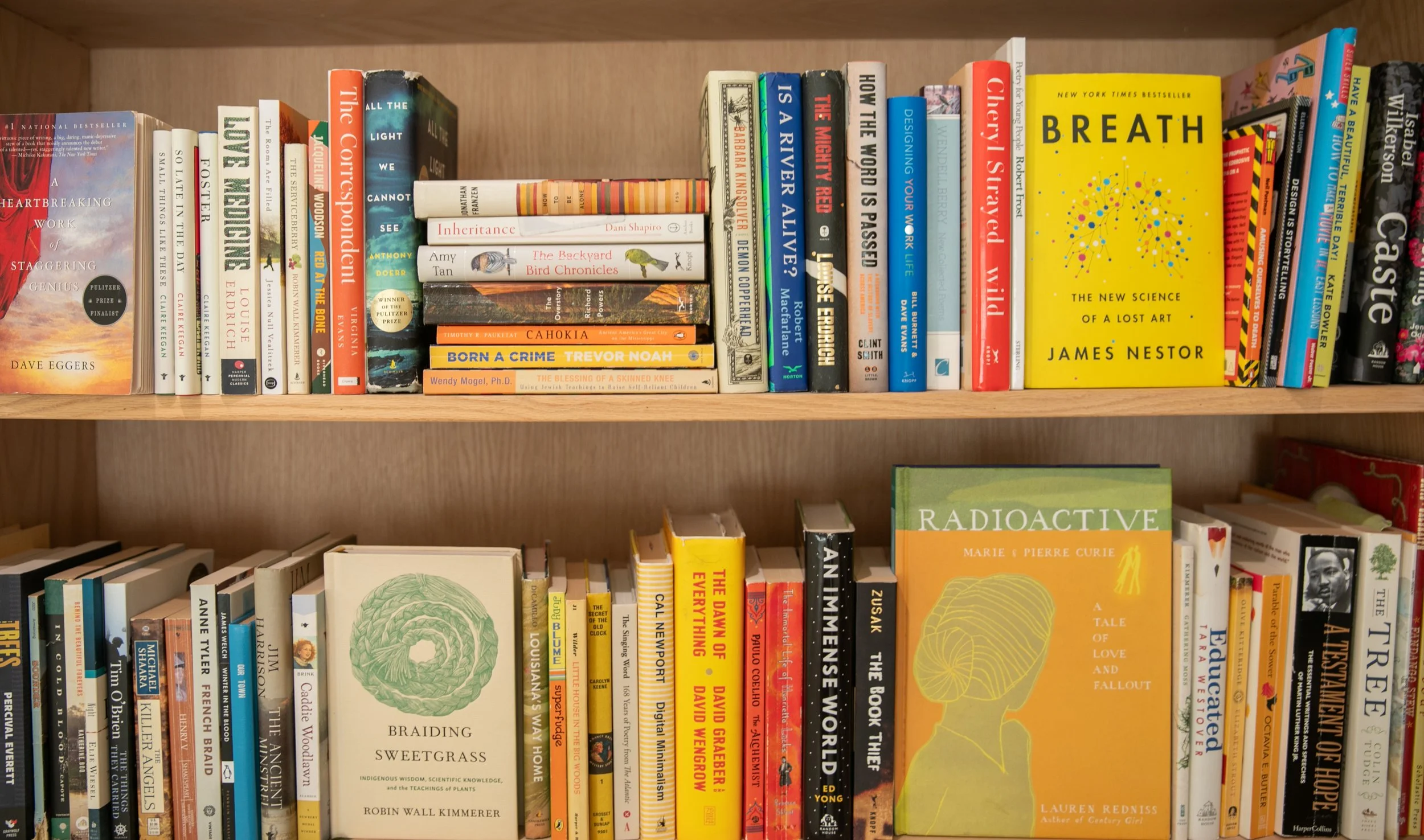 Bookshelf filled with various books, including fiction, non-fiction, and scientific titles, organized on a wooden shelf.