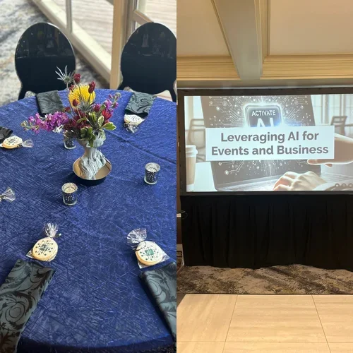 Table with a blue tablecloth and a vase of colorful flowers, surrounded by small decorated cookies and black chairs. Adjacent is a presentation screen displaying "Leveraging AI for Events and Business."