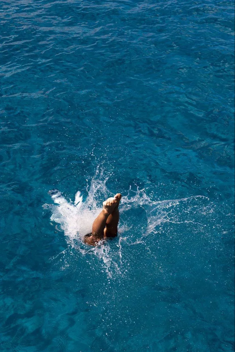 Person diving into a blue swimming pool with splash and ripples.