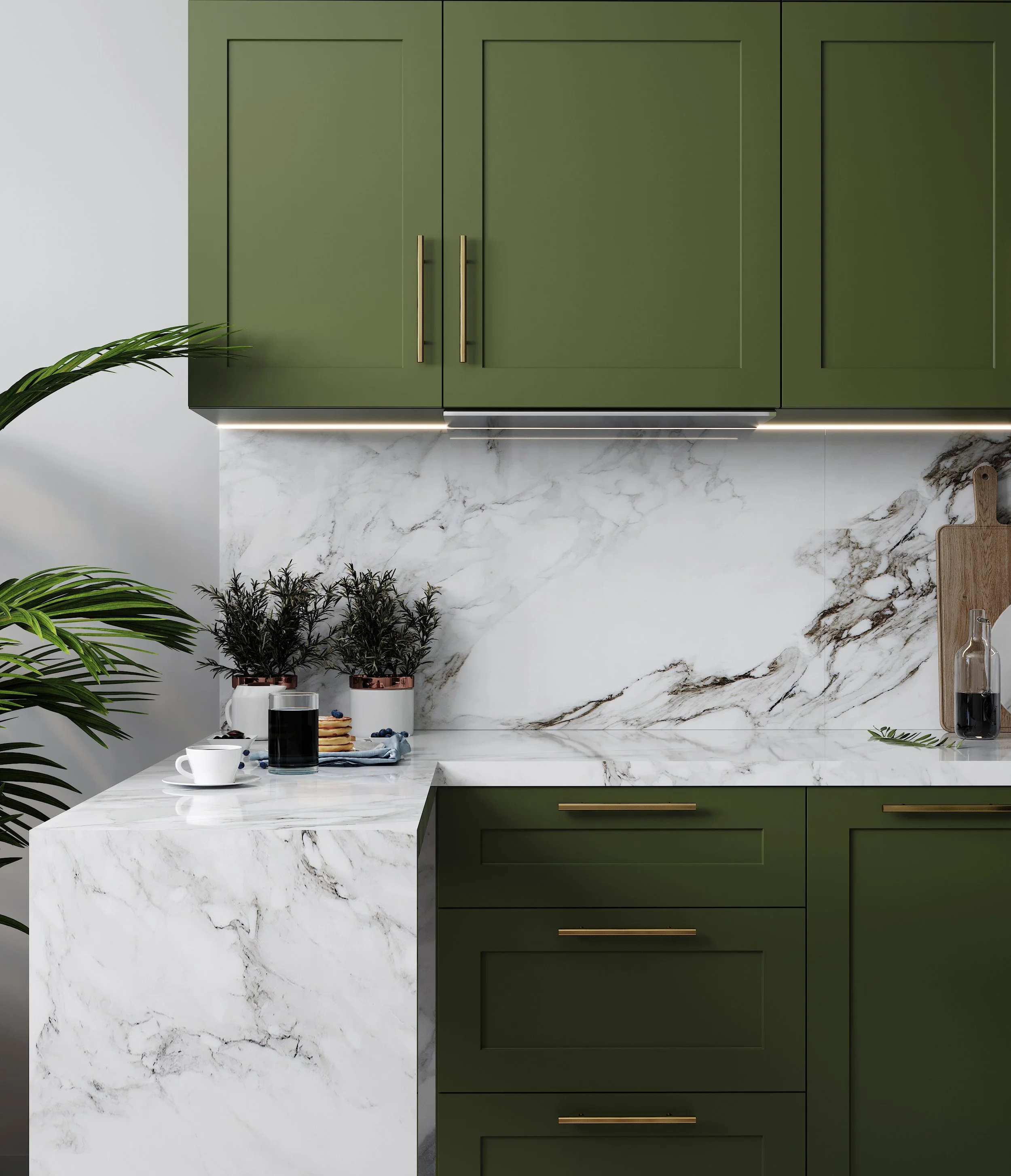 Modern kitchen with painted green cabinets, marble countertop and backsplash, plants, coffee, and pancakes on the counter.