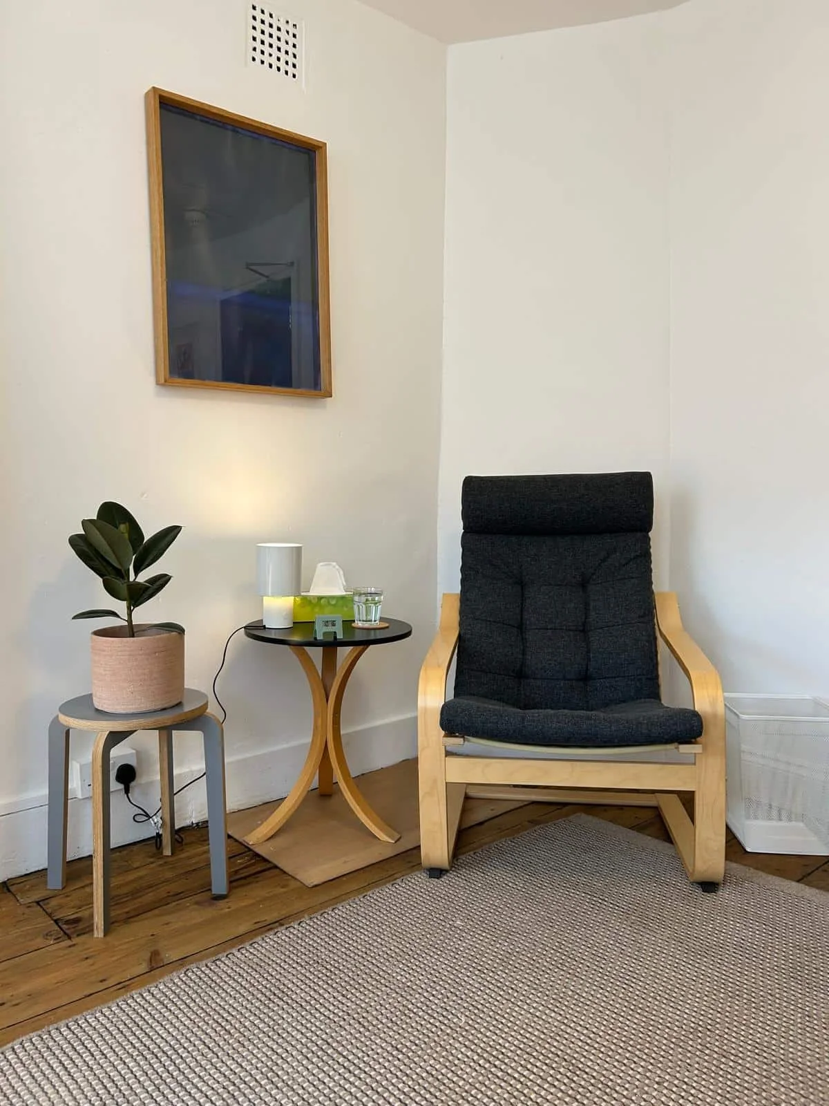A cozy corner in the therapy room with a black cushioned armchair.
