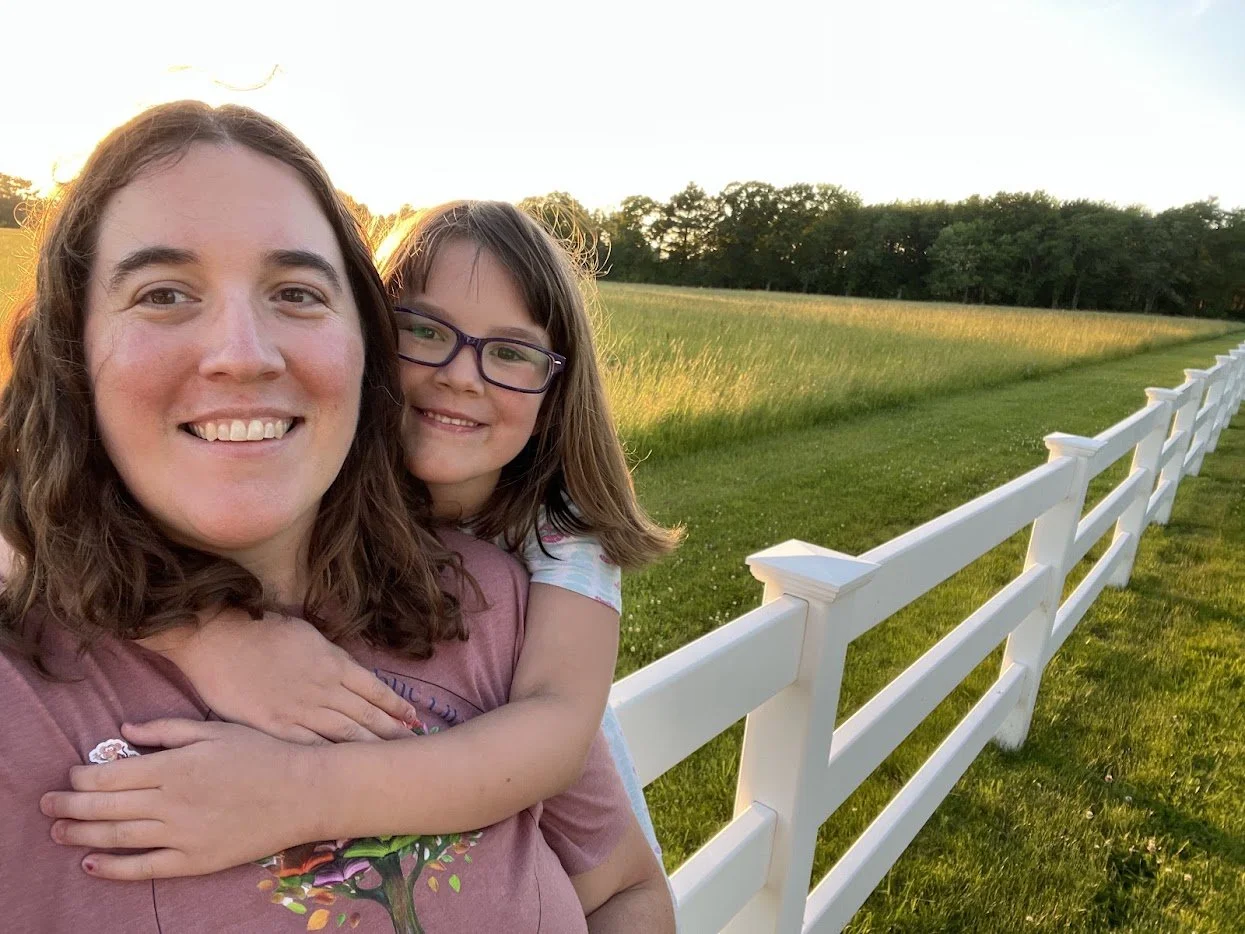 Leah and her daughter by a field in the sunset