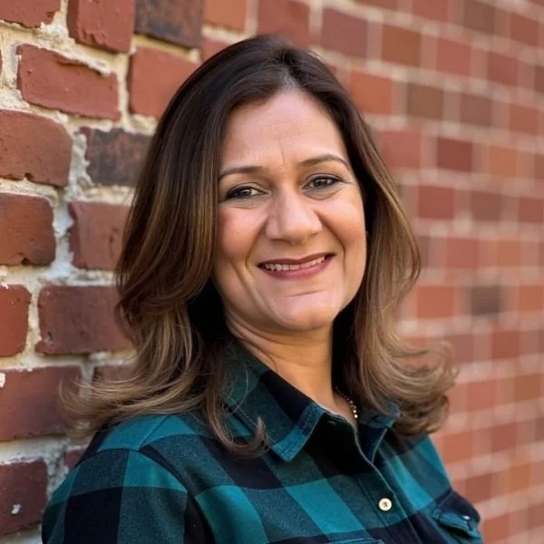 Monica Maheshwari, Career & Life Coach, smiling, standing outdoors against a brick wall.