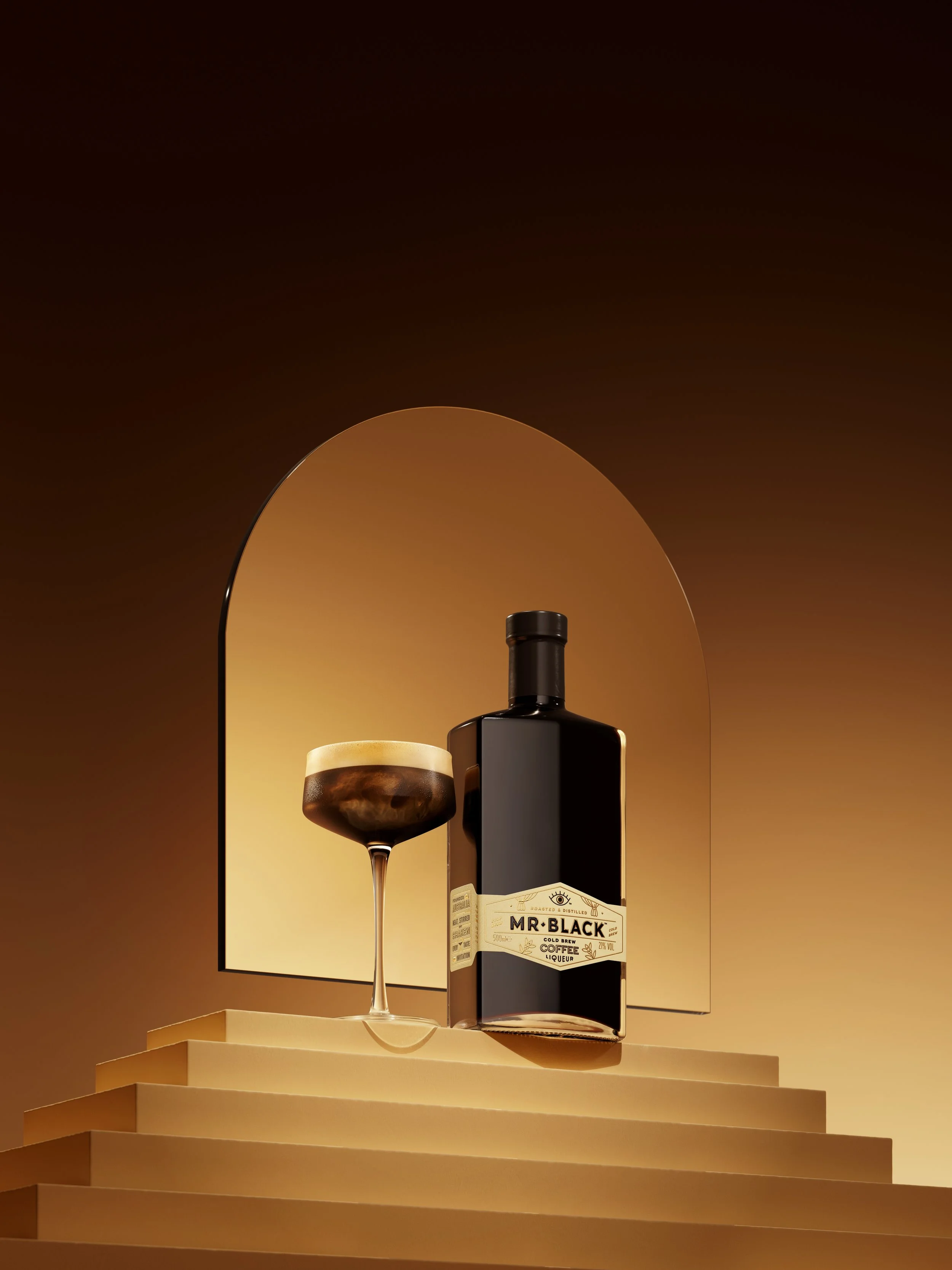 A bottle of Mr. Black cold brew coffee liqueur, a glass filled with a layered coffee and milk drink, and a mirror reflecting these items against a warm, gradient background.
