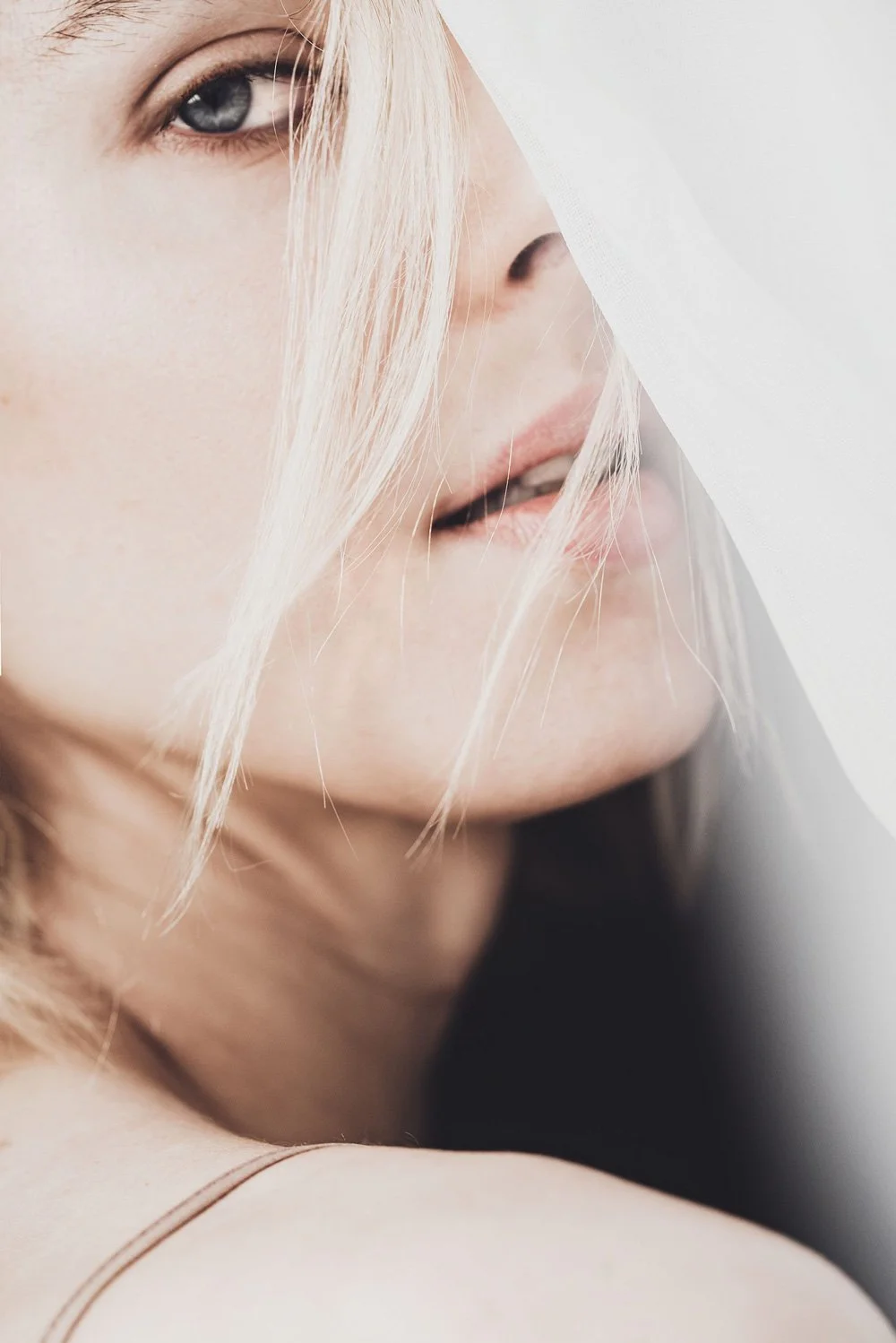 Close-up of Elsa Léger with blonde hair, looking to the side, with soft lighting and partially covered face.