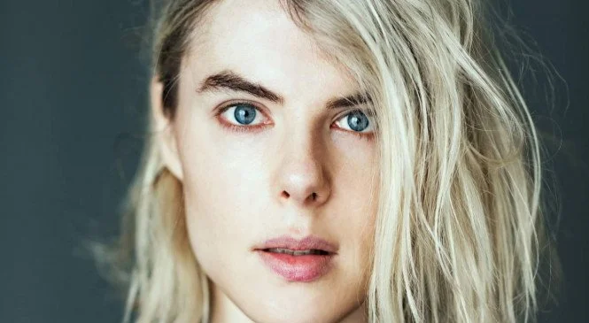 Close-up of a young Elsa Léger with blonde hair and blue eyes.