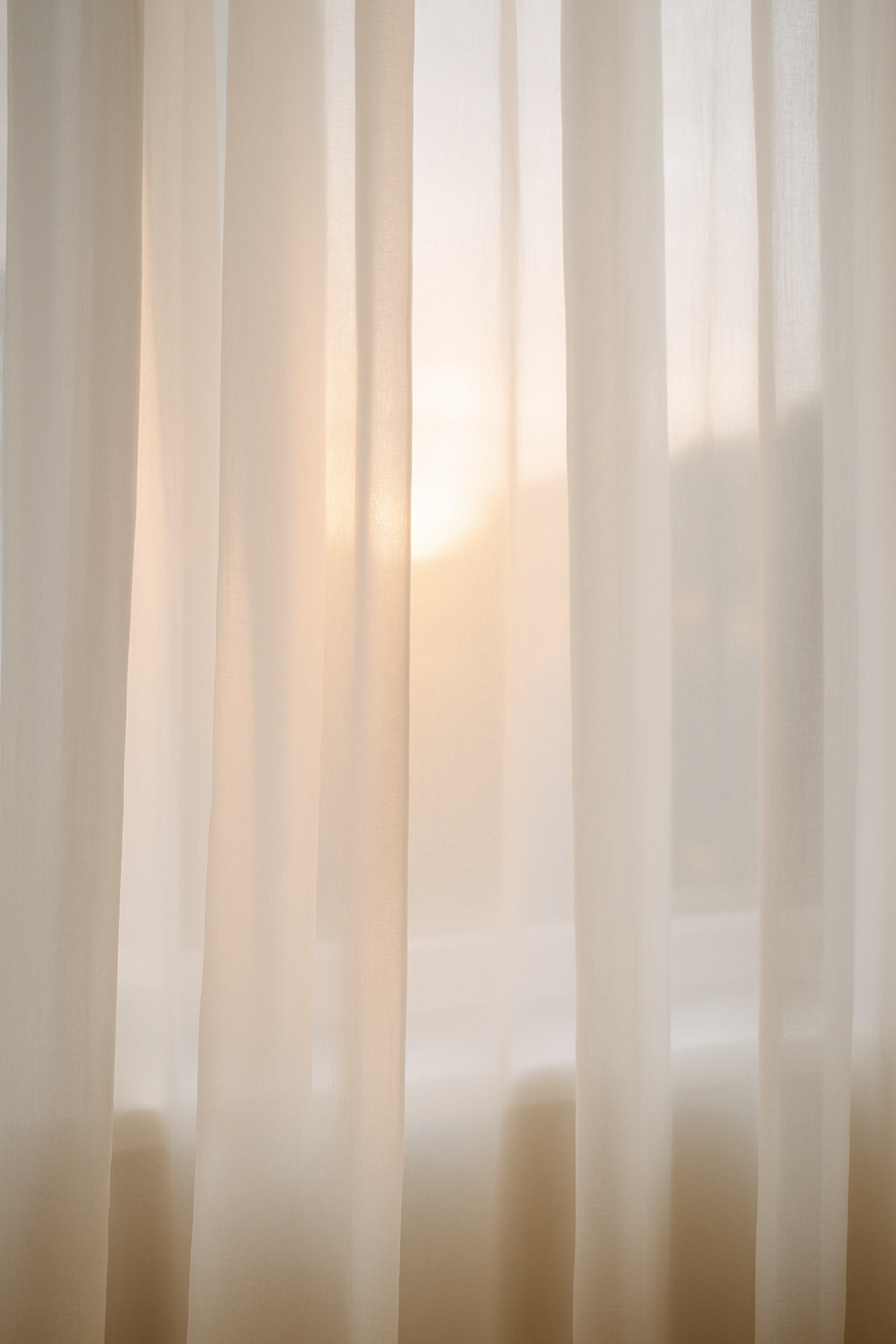Light-colored sheer curtains with sunlight shining through.