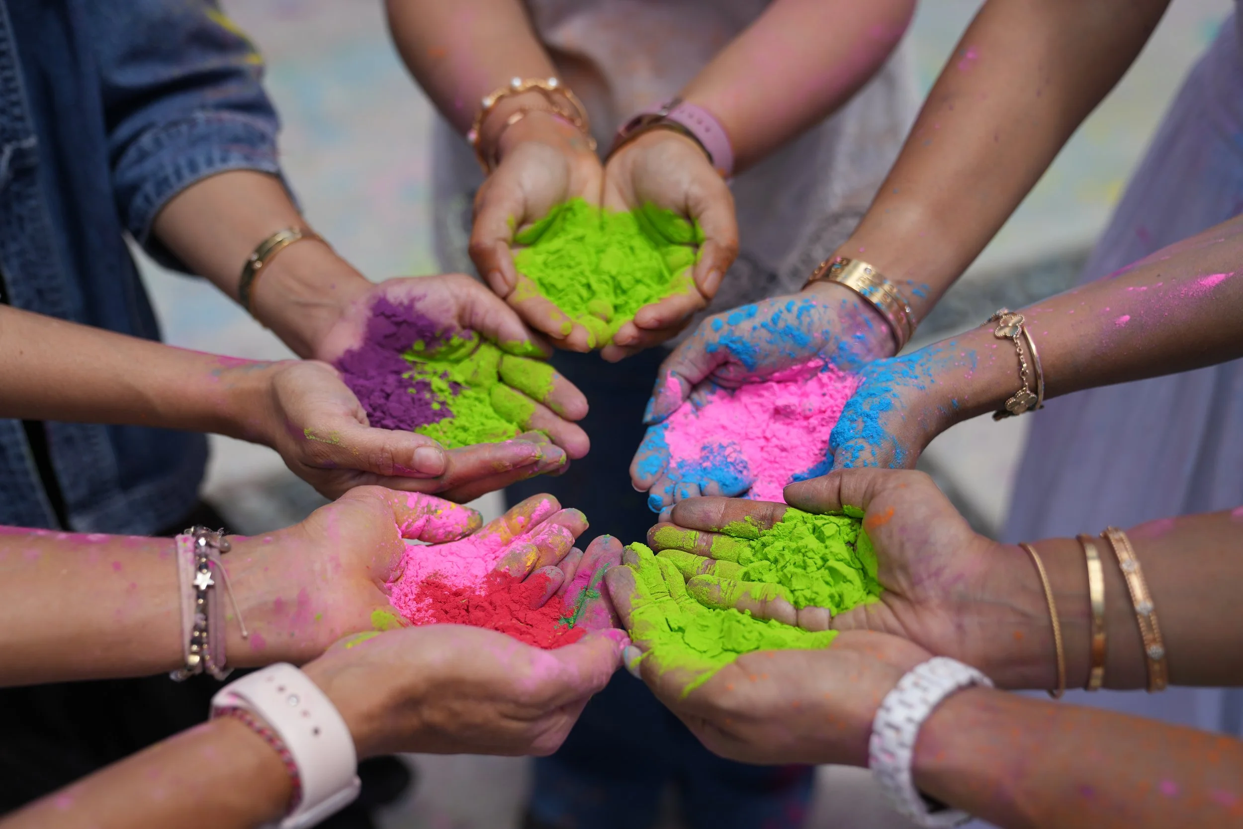 Hands covered in colorful powder, holding more powder, during a celebration or festival.