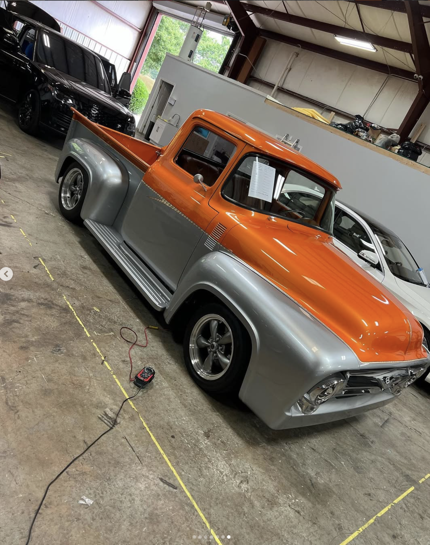 A vintage silver and orange pickup truck parked inside our workshop getting a full custom interior.