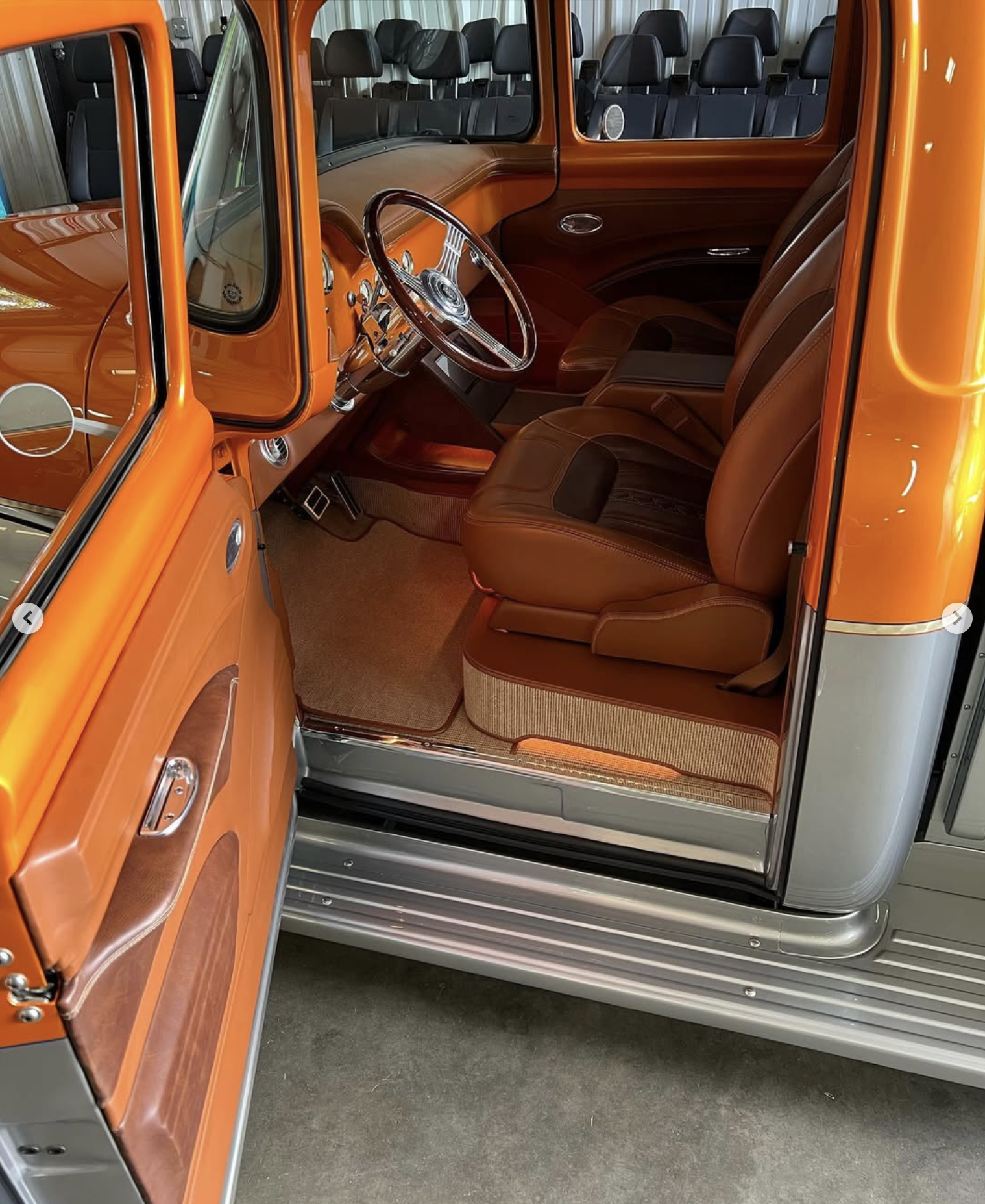The redone interior of a vintage truck, showcasing custom stitched brown leather seats, a custom stitched and rebuilt brown dashboard, and a wooden steering wheel.