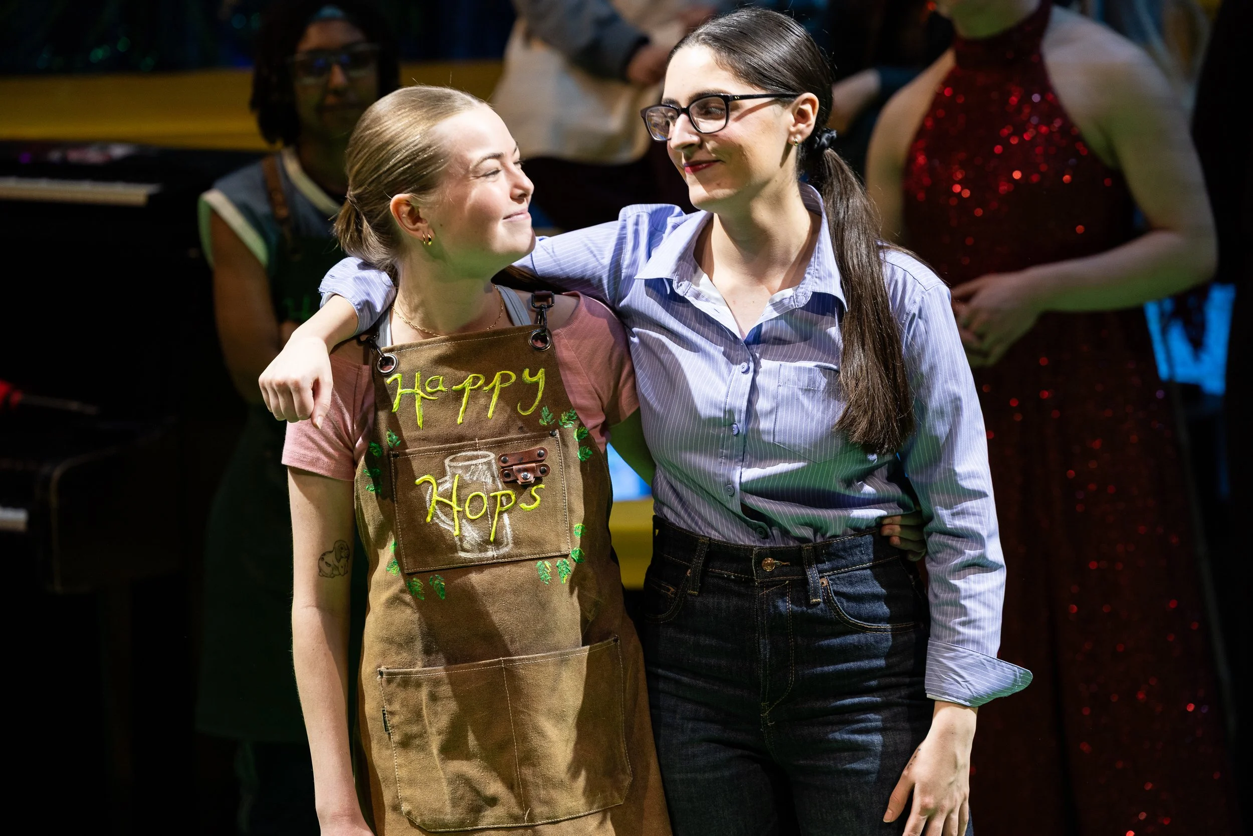 Two women embrace and look at each other happily on stage during a performance or event.