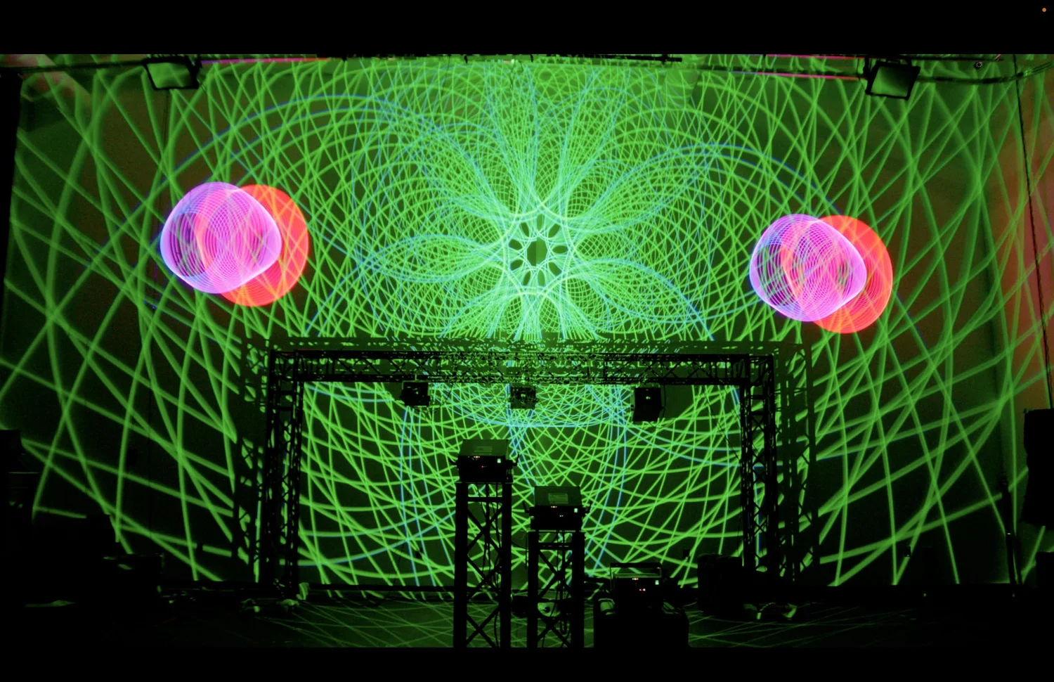 Green laser patterns and pink luminous forms fill the room during ANIMALCULE