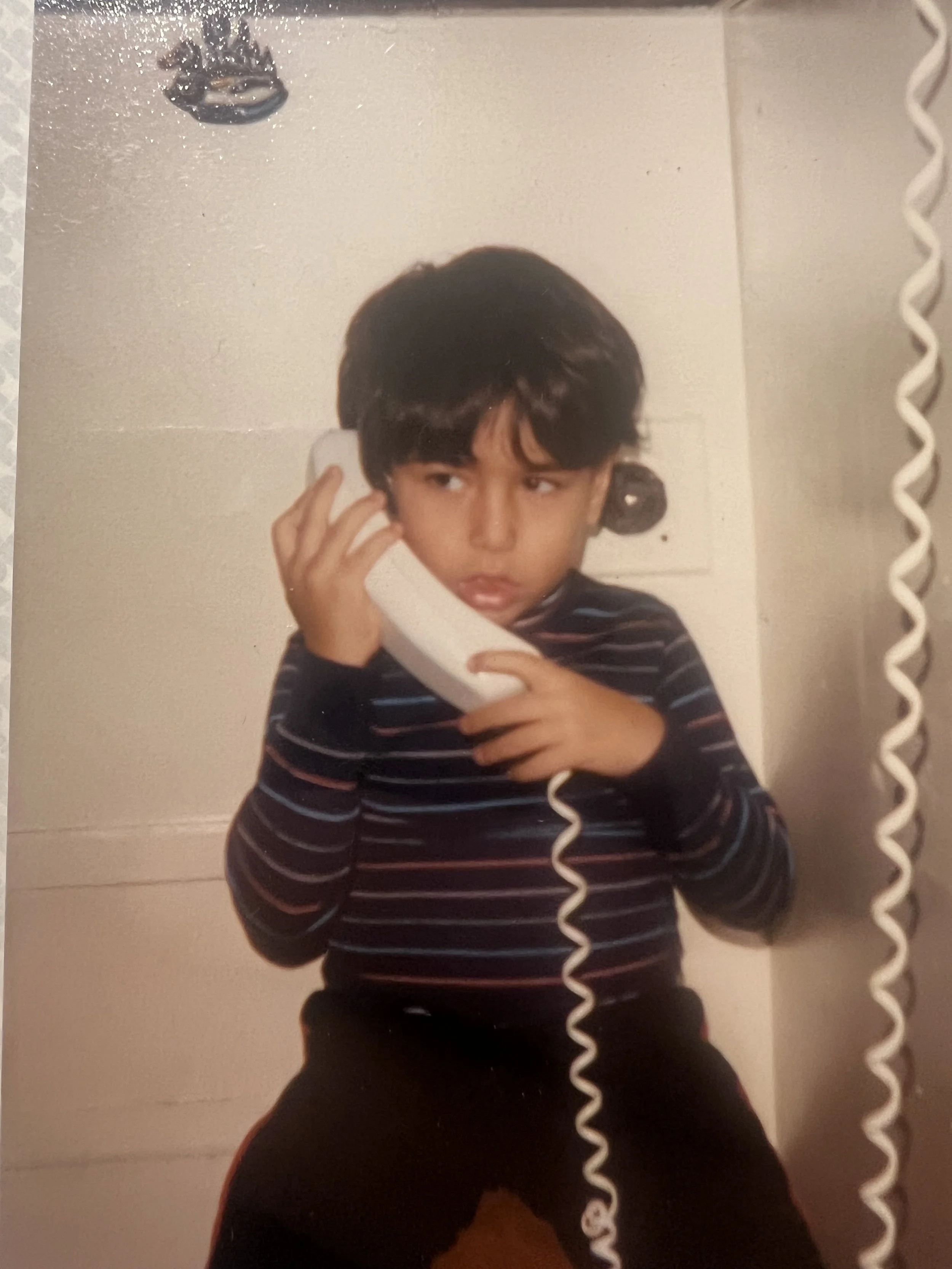 Ramtin as a child holding a telephone receiver